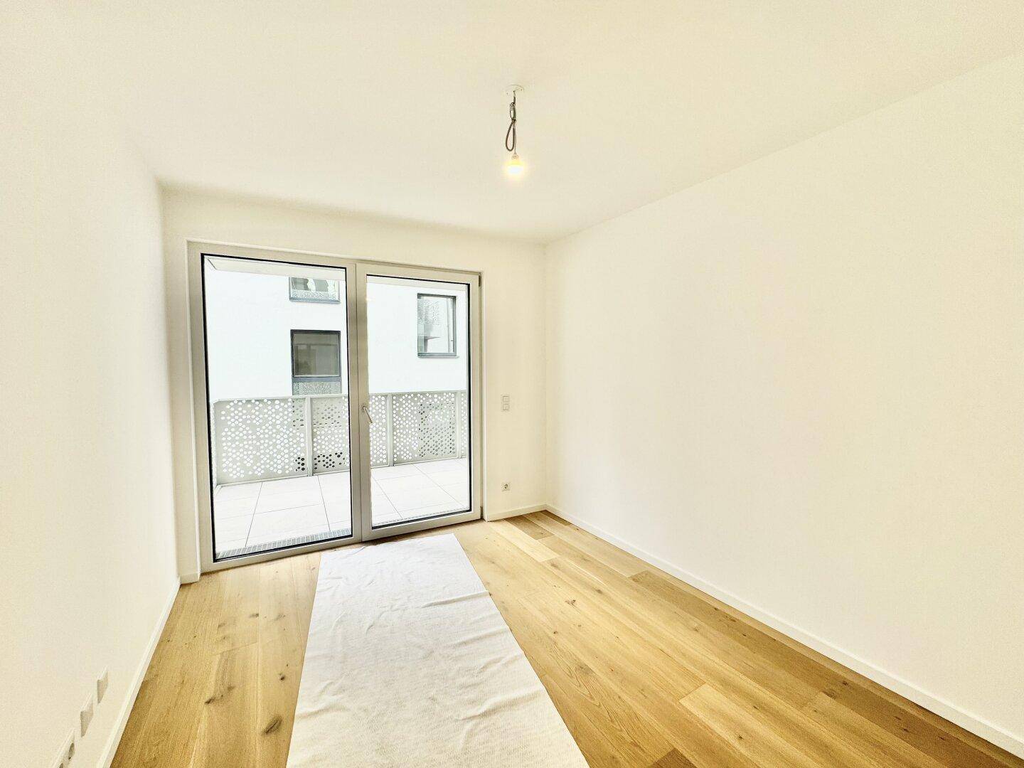 Heller Raum mit Holzboden und direktem Zugang zu einem Balkon, ideal für viel Tageslicht.