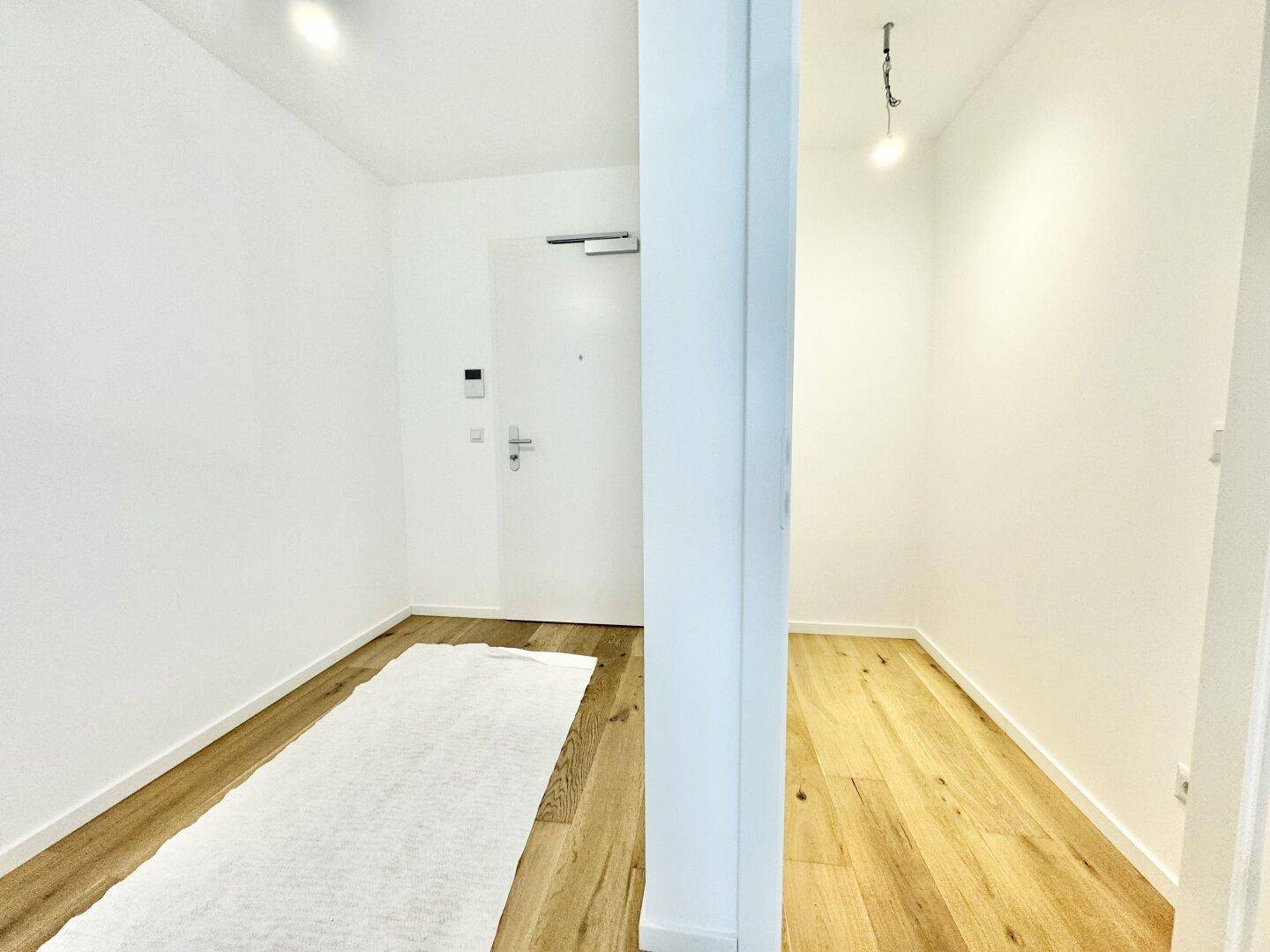 Heller Flur mit Holzboden und einem kleinen Abstellbereich, der zu weiteren Räumen führt.