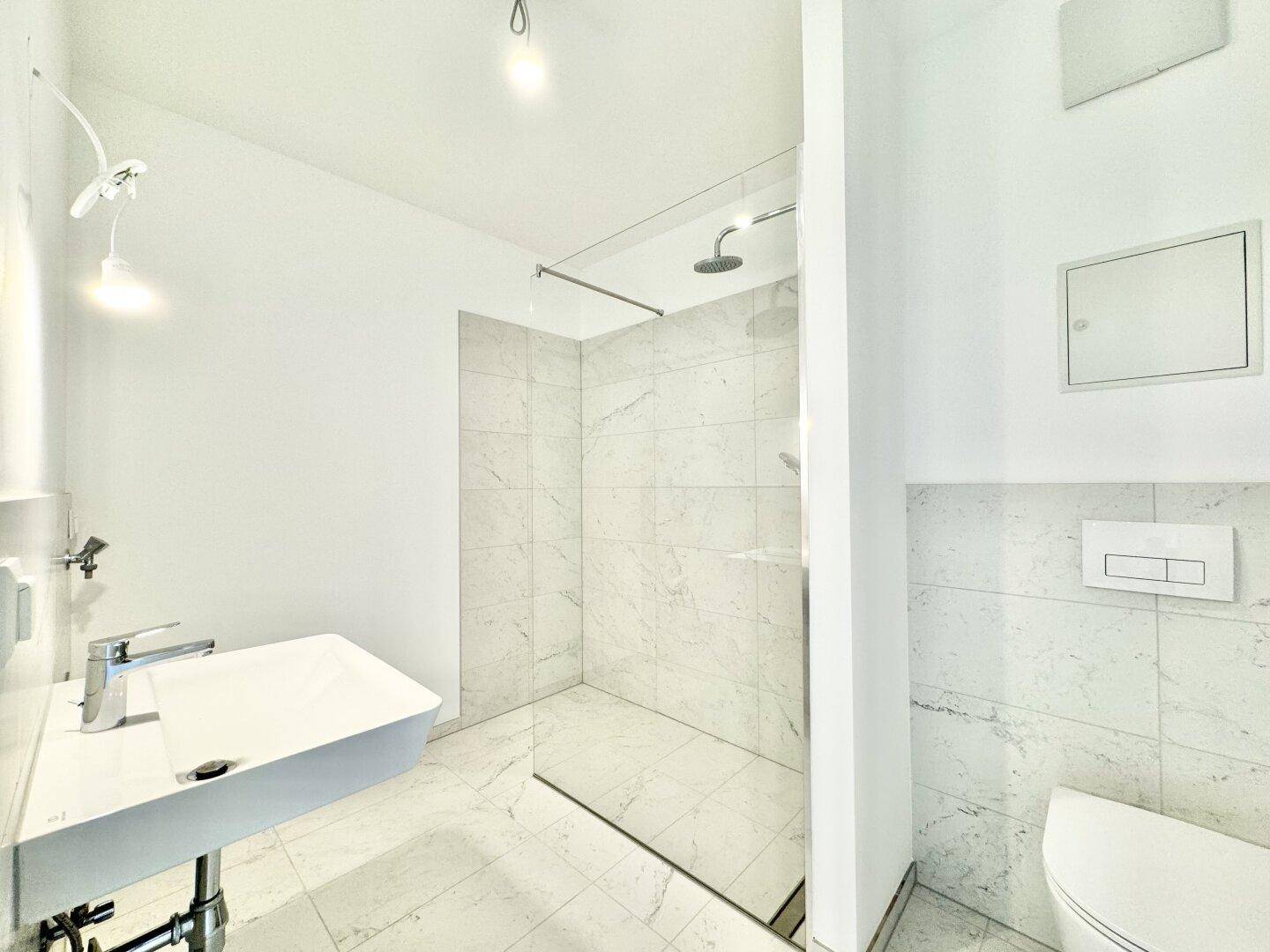 Modernes Badezimmer mit begehbarer Dusche, Marmorfliesen und Wand-WC.