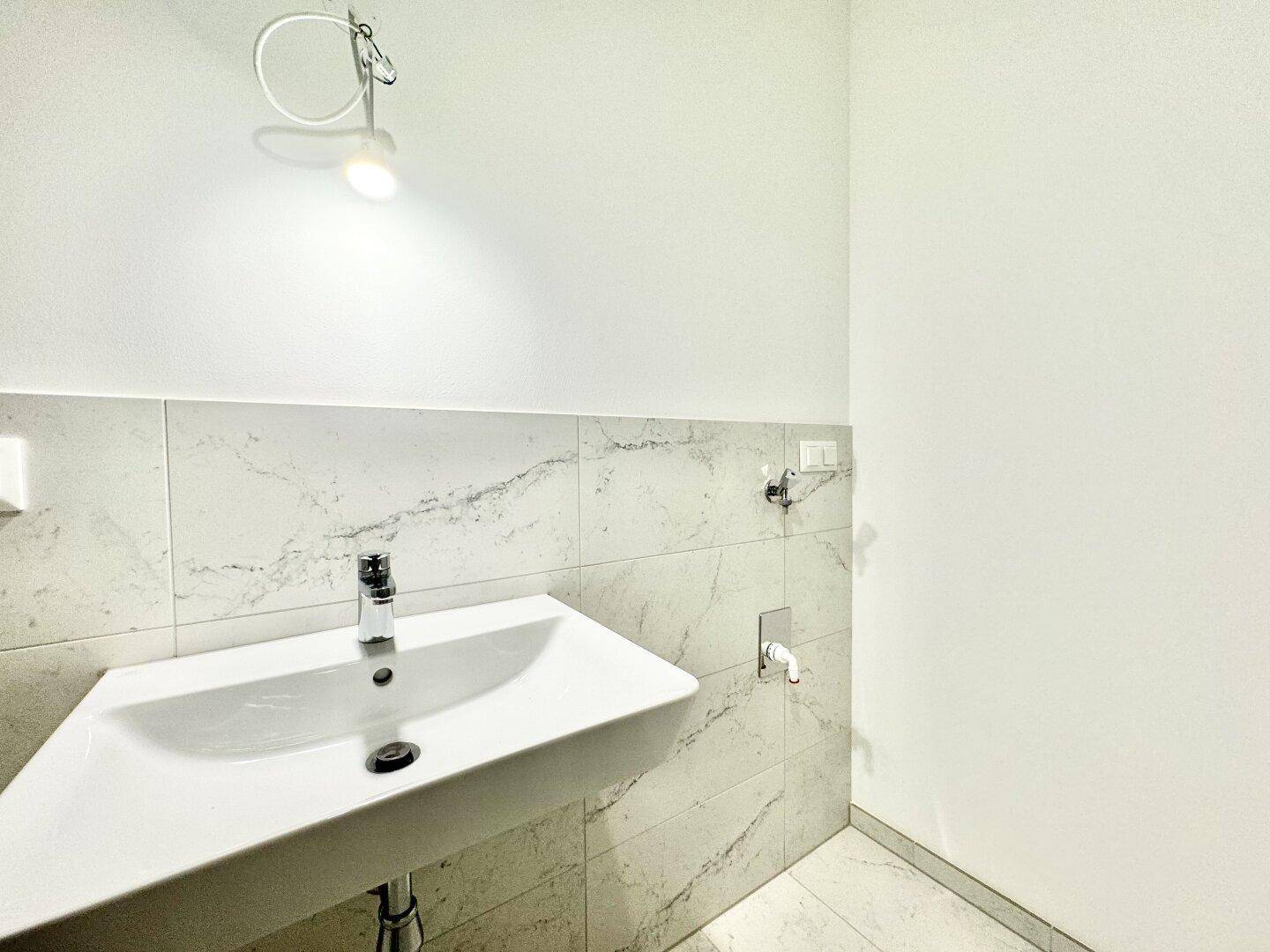 Detailansicht des modernen Waschtischs mit Armatur und Marmorfliesen im Badezimmer.