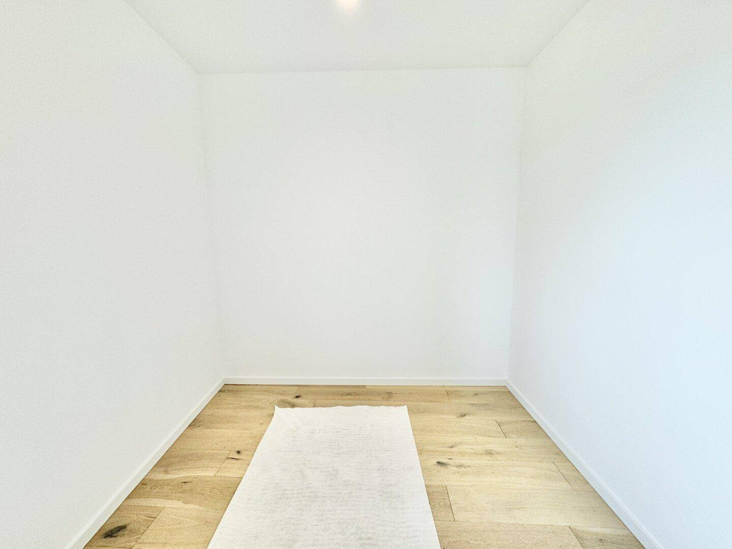 Kleiner, heller Raum mit Holzboden, ideal als Abstellraum oder begehbarer Kleiderschrank.