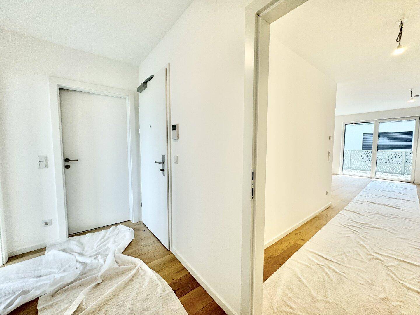 Eingangsbereich mit Holzboden und weißen Türen, der zu verschiedenen Räumen führt.