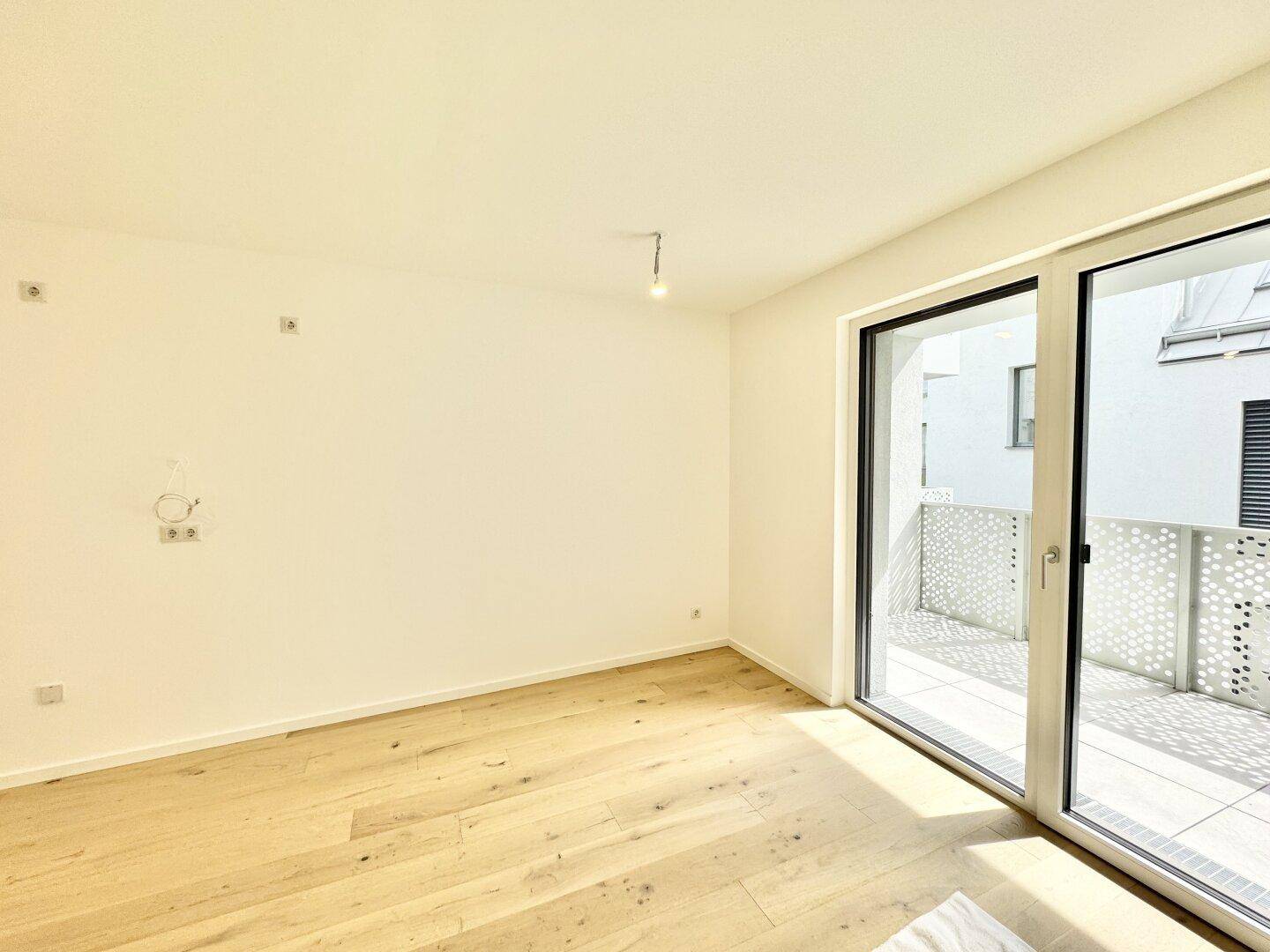 Lichtdurchflutetes Zimmer mit Holzboden und Zugang zu einem Außenbereich.