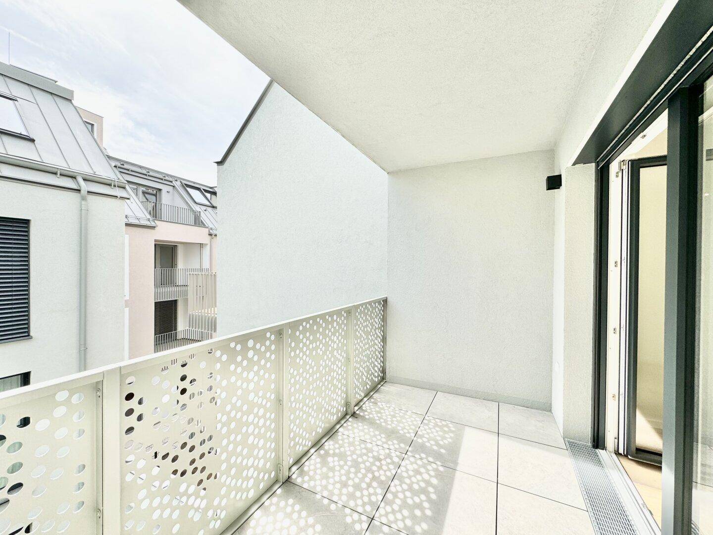 Heller Balkon mit modernem Lochblechgeländer und Zugang zum Innenraum.