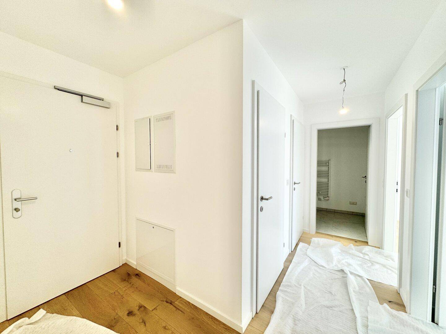 Heller Flur mit Holzboden und mehreren Türen, der verschiedene Räume der Wohnung verbindet.