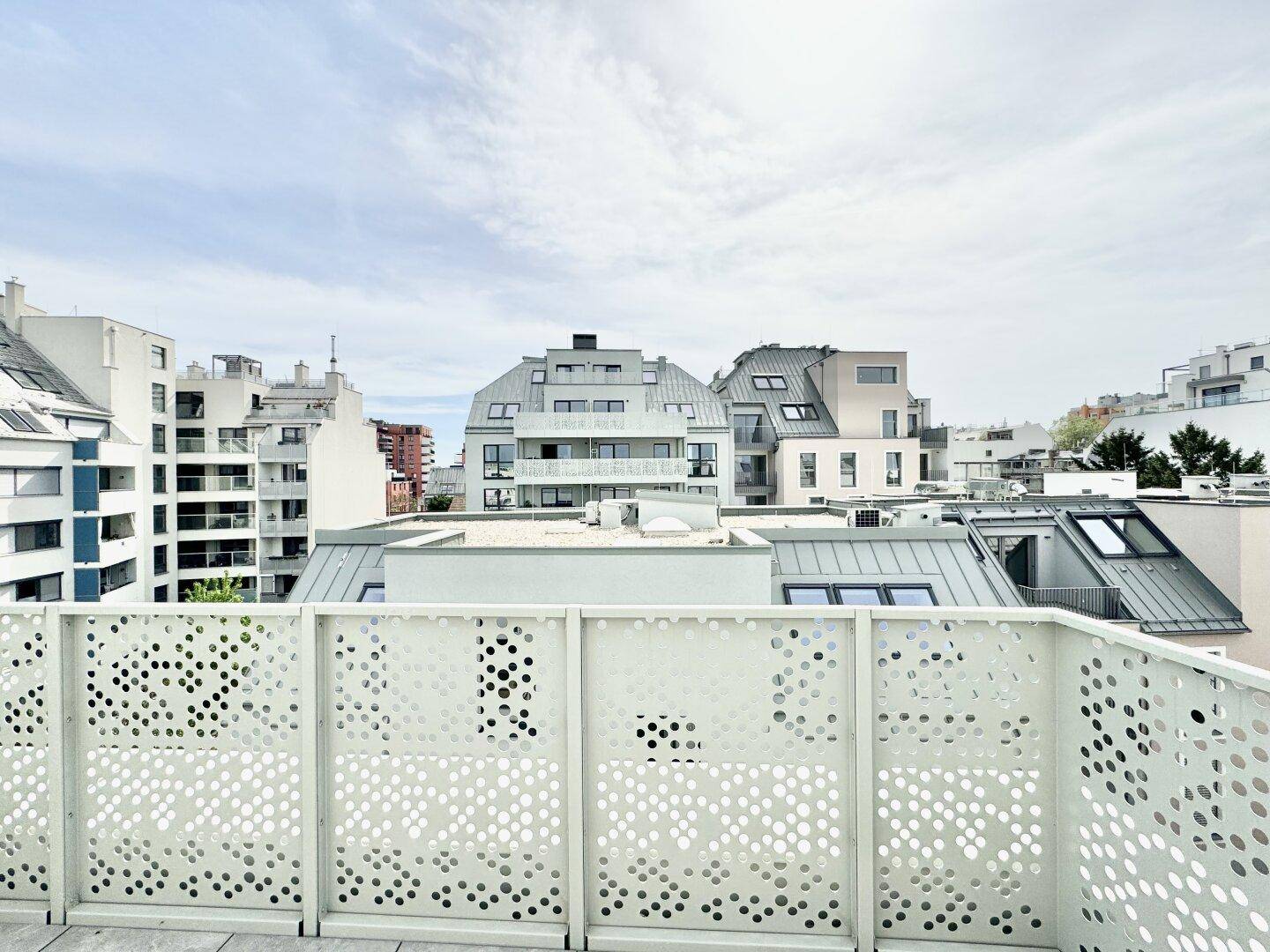 Blick von einem Balkon auf die umliegenden modernen Gebäude und Dächer der Stadtlandschaft.