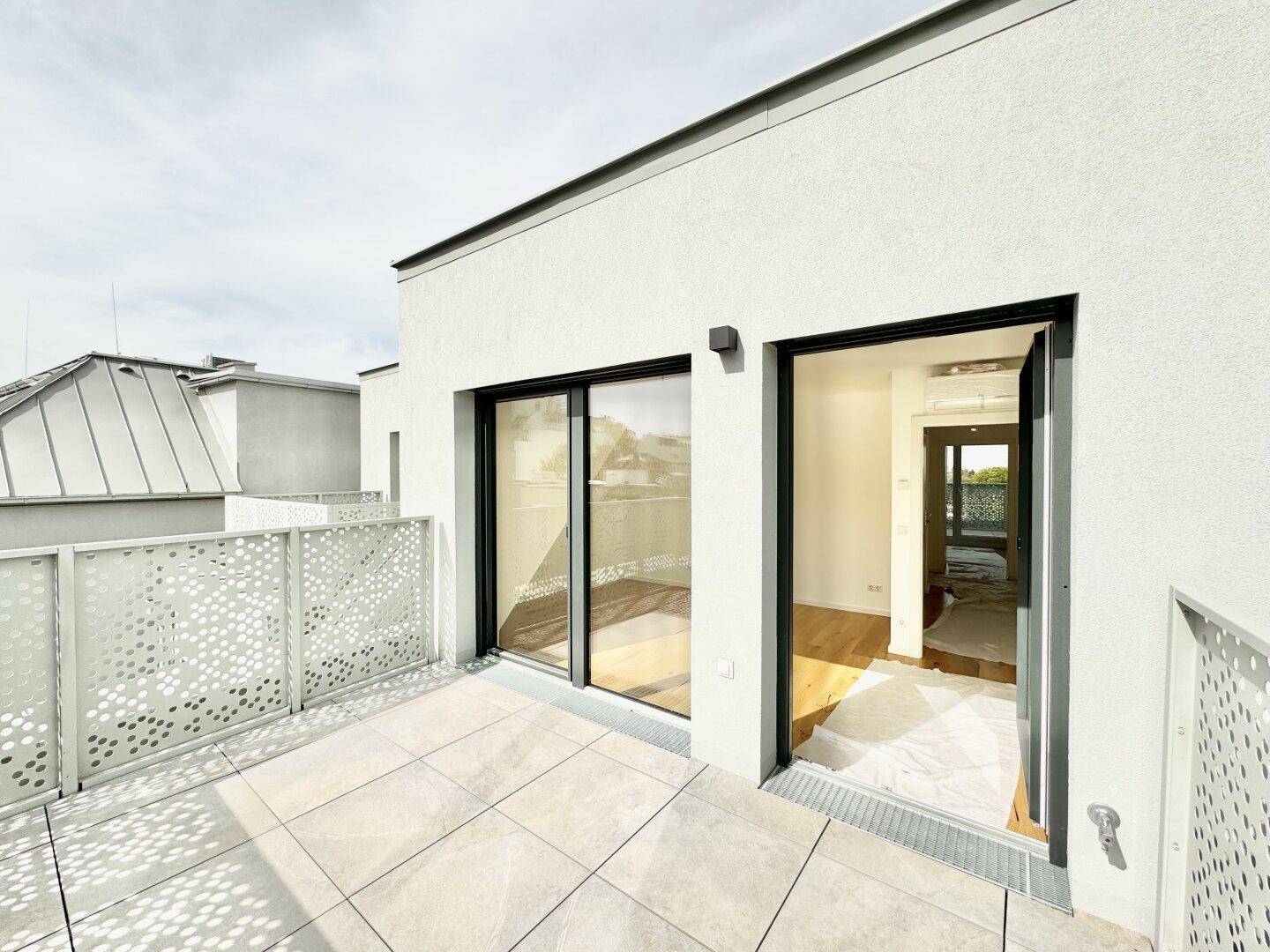Geräumiger Balkon mit Fliesenboden und direktem Zugang zu einem hellen Innenraum durch Glastüren.