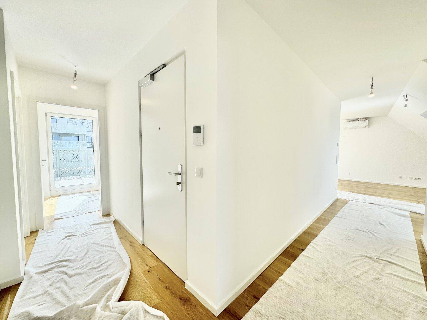 Heller Flur mit Holzboden und moderner Eingangstür, führt zu weiteren Räumen der Wohnung.