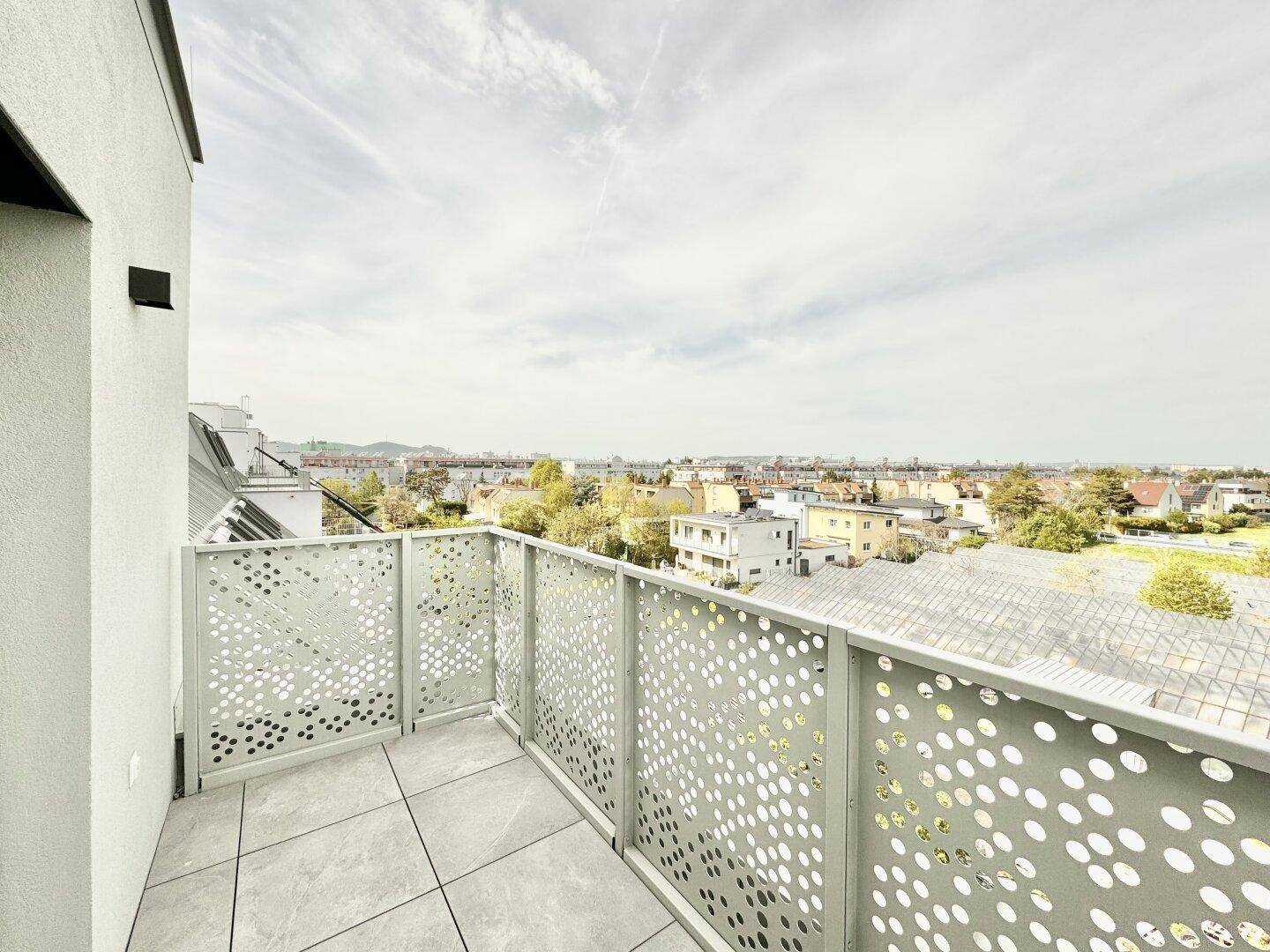 Geräumiger Balkon mit Fliesenboden und moderner Lochblech-Brüstung, bietet einen weiten Stadtblick.