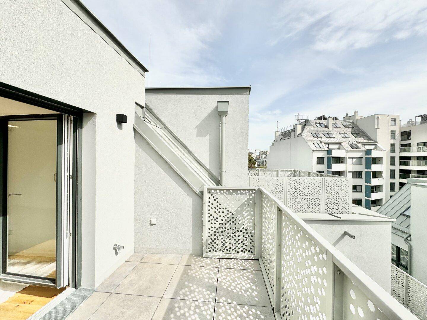 Geräumige Dachterrasse mit Fliesenboden und modernem Geländer, ideal für Entspannung im Freien.