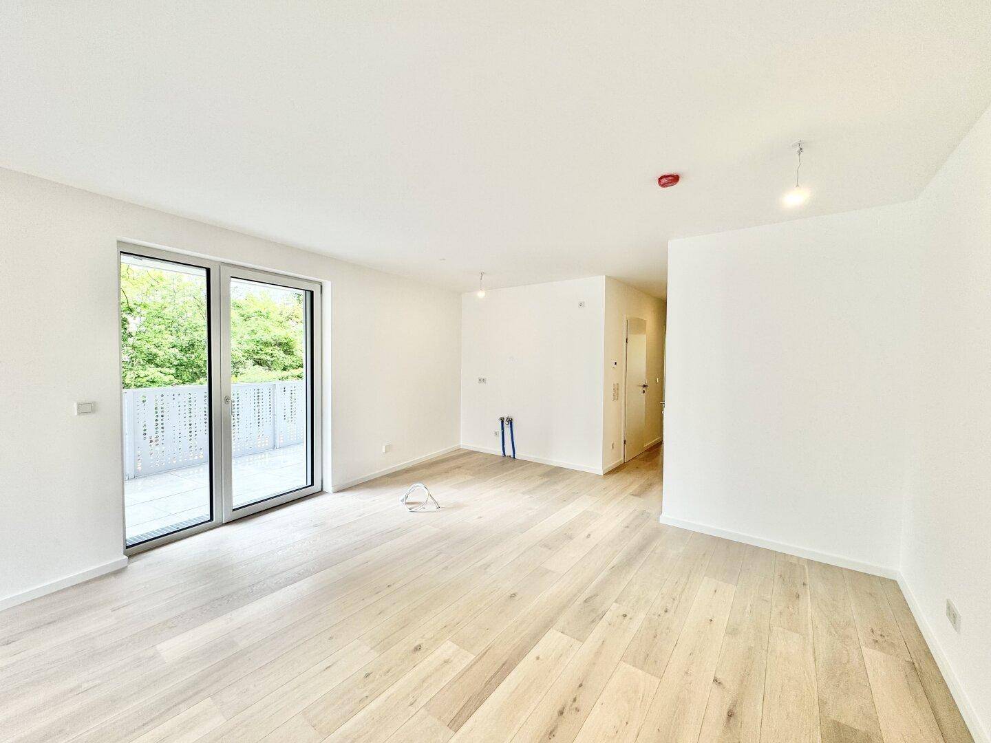 Lichtdurchfluteter Wohnraum mit Holzboden und direktem Zugang zu einem sonnigen Balkon.
