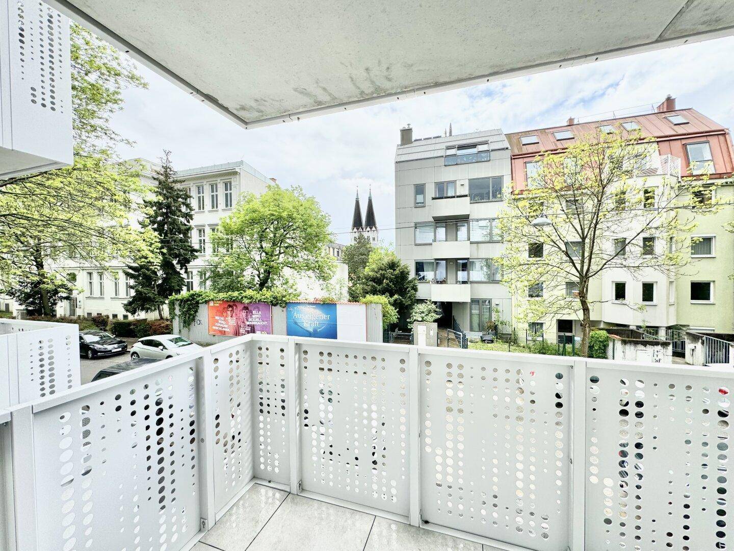 Balkon mit Stadtblick und Sicht auf historische Gebäude sowie einen markanten Kirchturm.