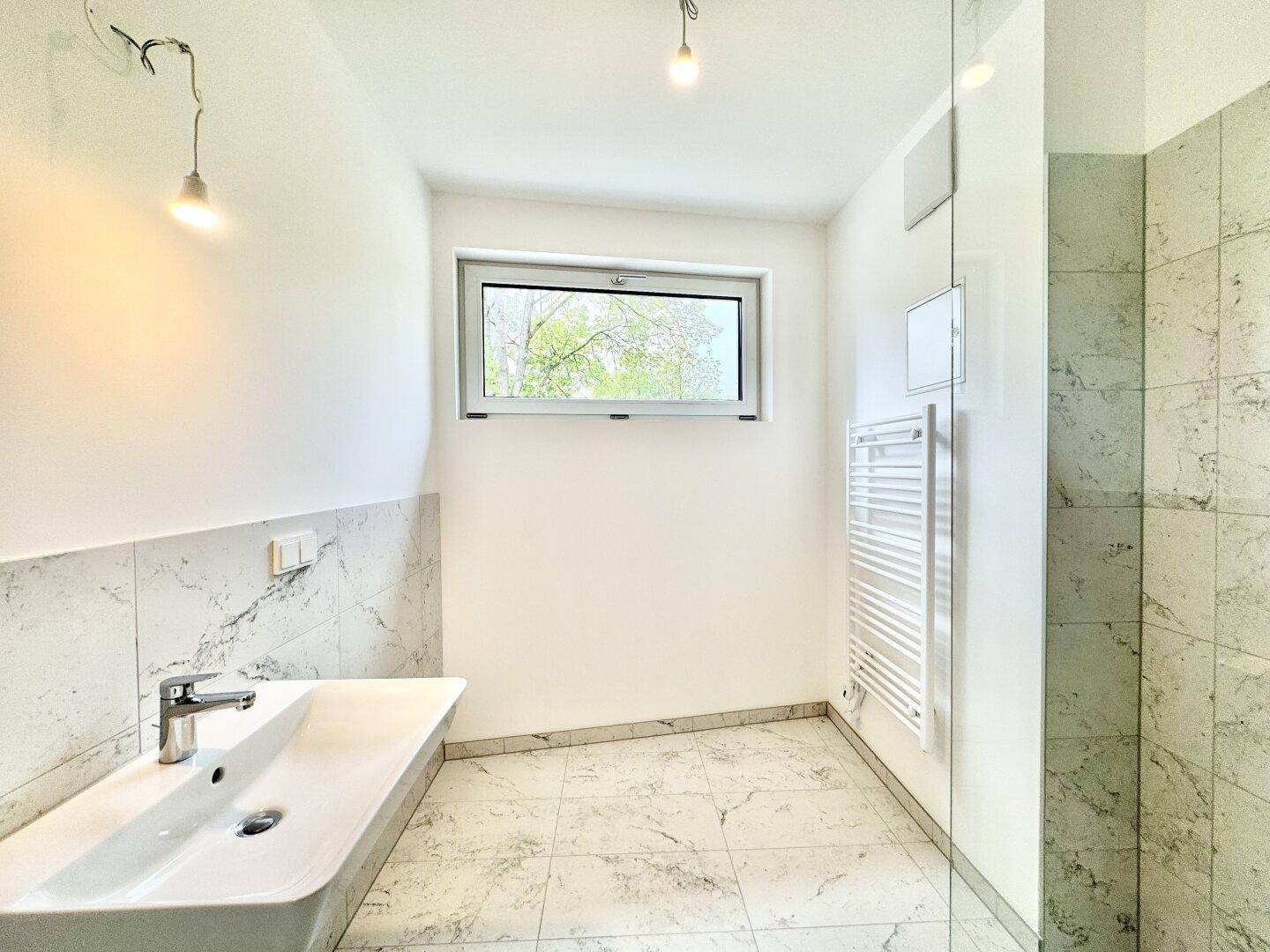 Modernes Badezimmer mit Fenster, Einzelwaschbecken und praktischem Handtuchheizkörper.