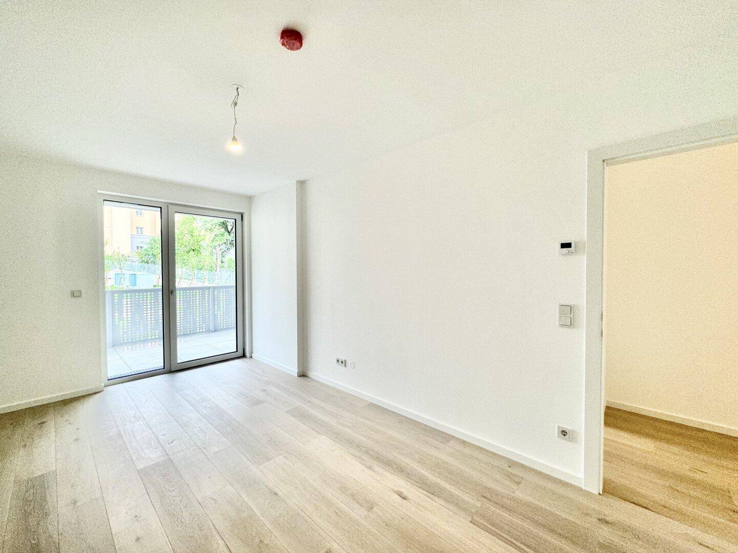 Geräumiges Schlafzimmer mit hellem Parkettboden und Zugang zu einem sonnigen Balkon.