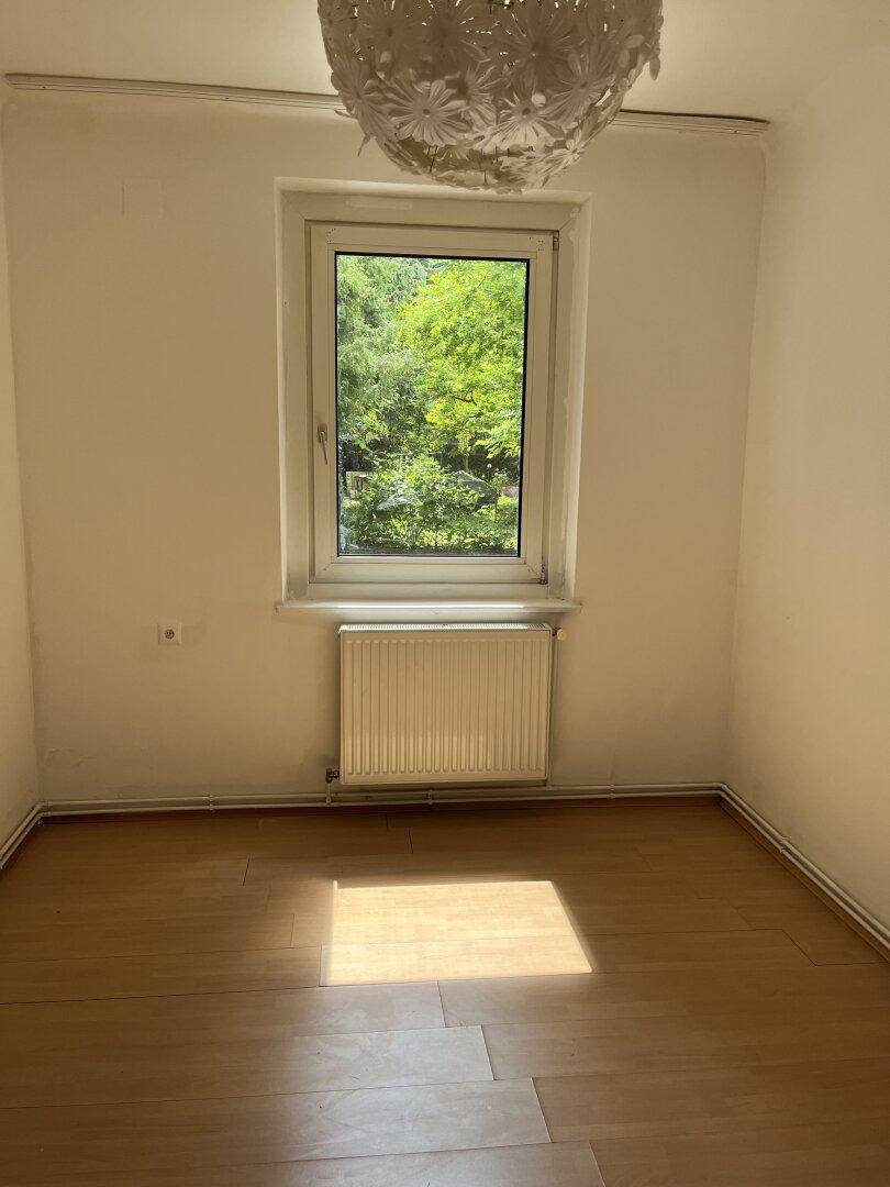 Helles Schlafzimmer mit Holzfußboden, einem Fenster und viel natürlichem Licht.