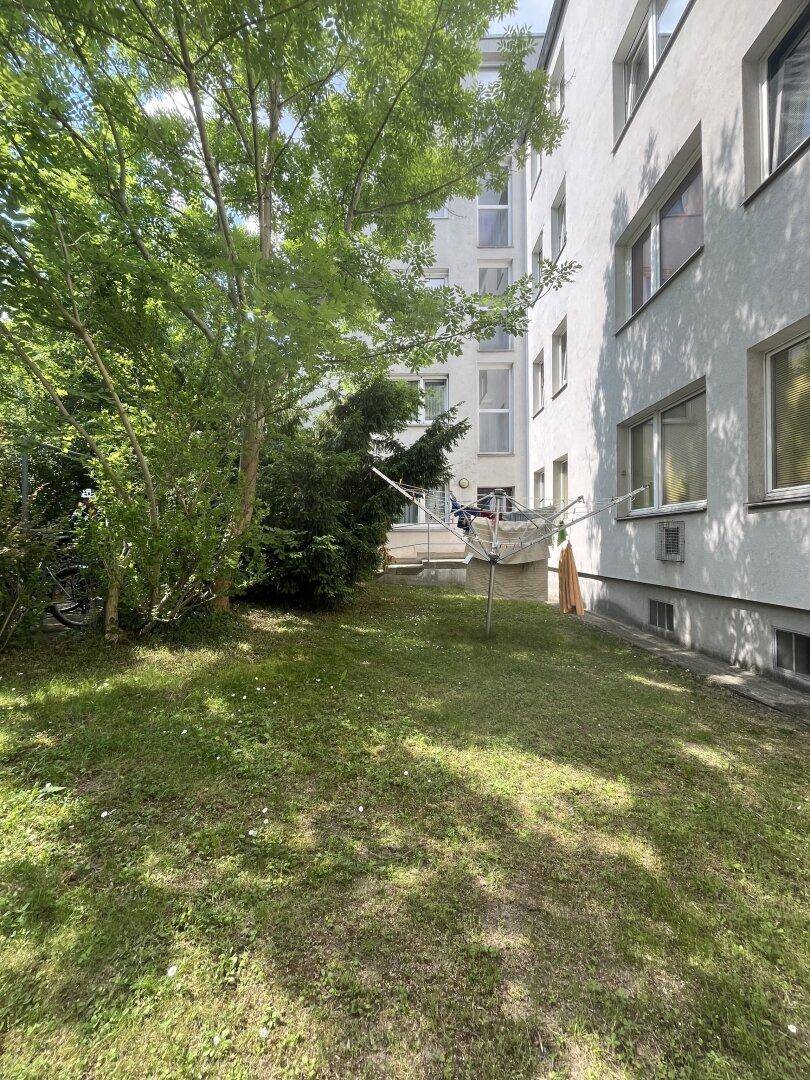 Außenansicht eines Wohnhauses mit Rasenfläche und Wäscheleinen im Vordergrund.