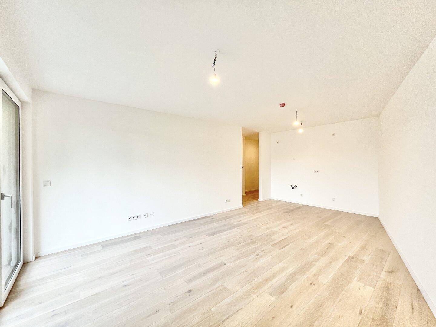 Geräumiges, unmöbliertes Zimmer mit hellem Holzboden und weiß gestrichenen Wänden, bereit zur Einrichtung.