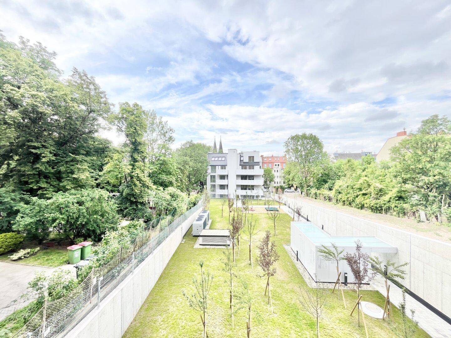 Weitläufiger Blick über die grüne Umgebung mit modernen Gebäuden und einem gepflegten Gartenbereich.