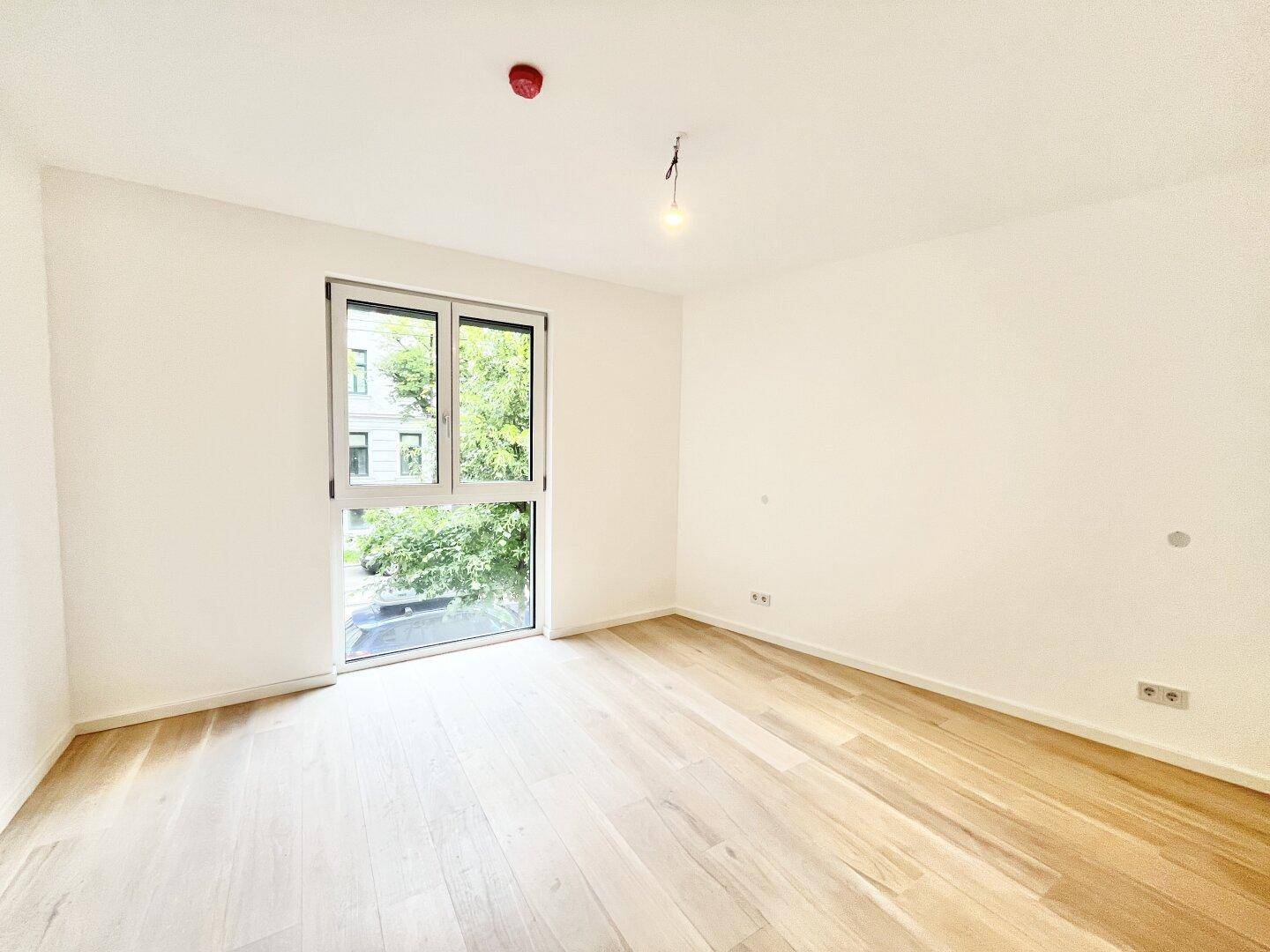 Helles Schlafzimmer mit großem Fenster und Blick ins Grüne, bietet viel Tageslicht und Ruhe.
