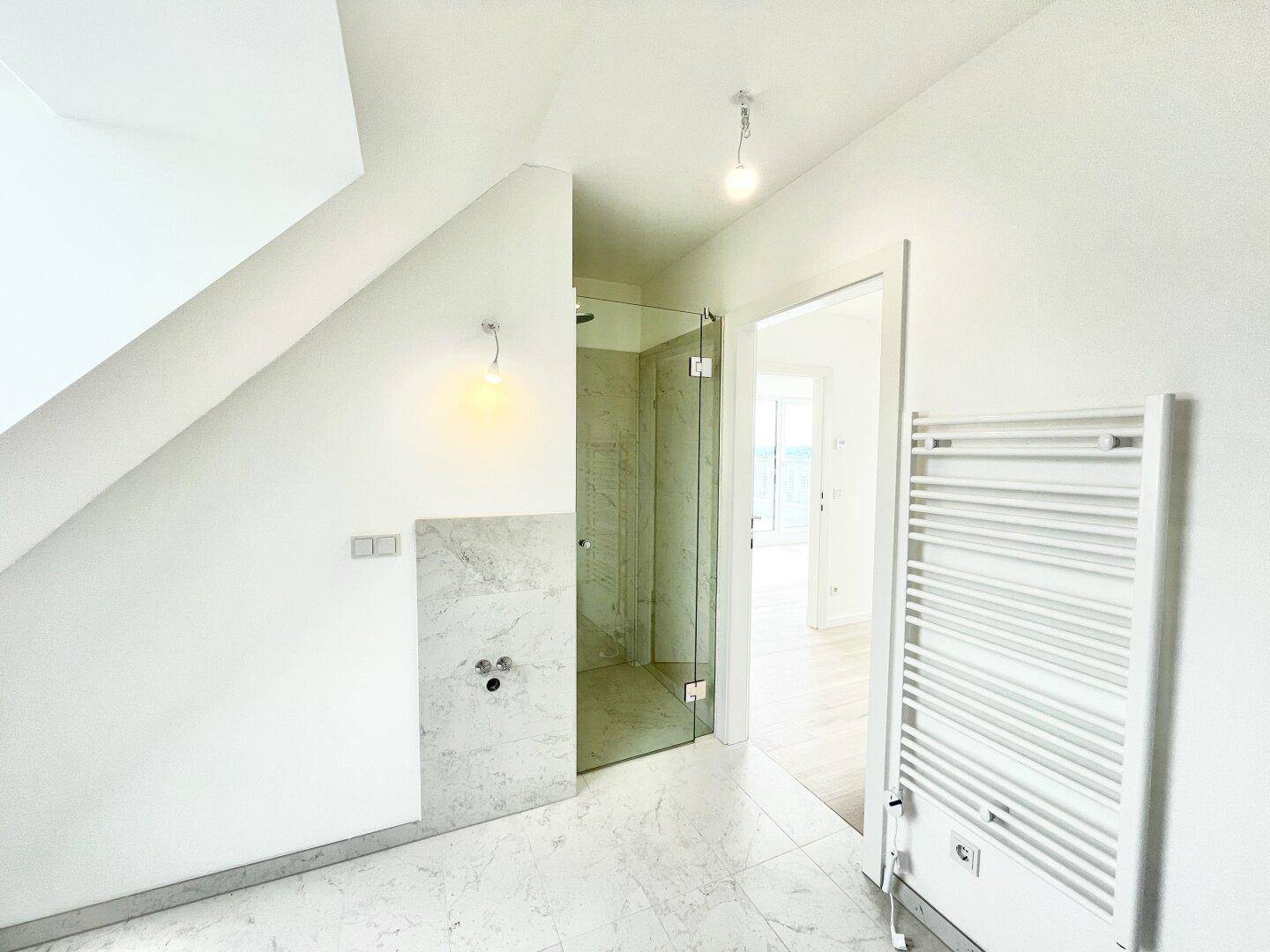 Modernes Badezimmer mit Marmorfliesen, begehbarer Dusche und beheiztem Handtuchhalter unter Dachschräge.