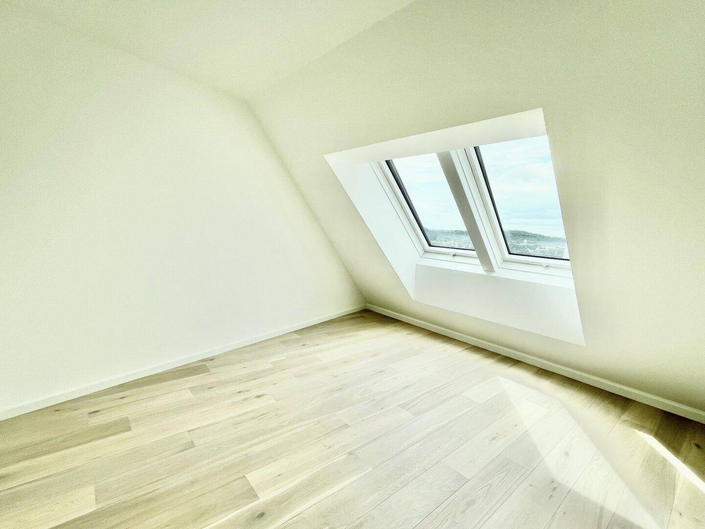 Lichtdurchfluteter Raum mit Holzboden und Dachfenster, bietet eine helle und ruhige Atmosphäre.