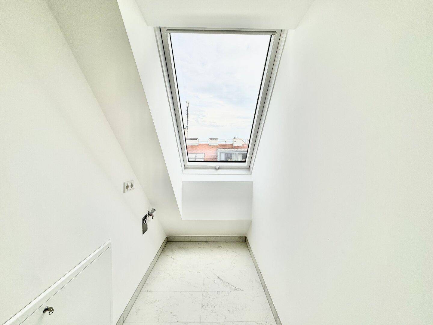 Kleiner, heller Abstellraum mit Fliesenboden und Dachfenster, bietet zusätzlichen Stauraum.