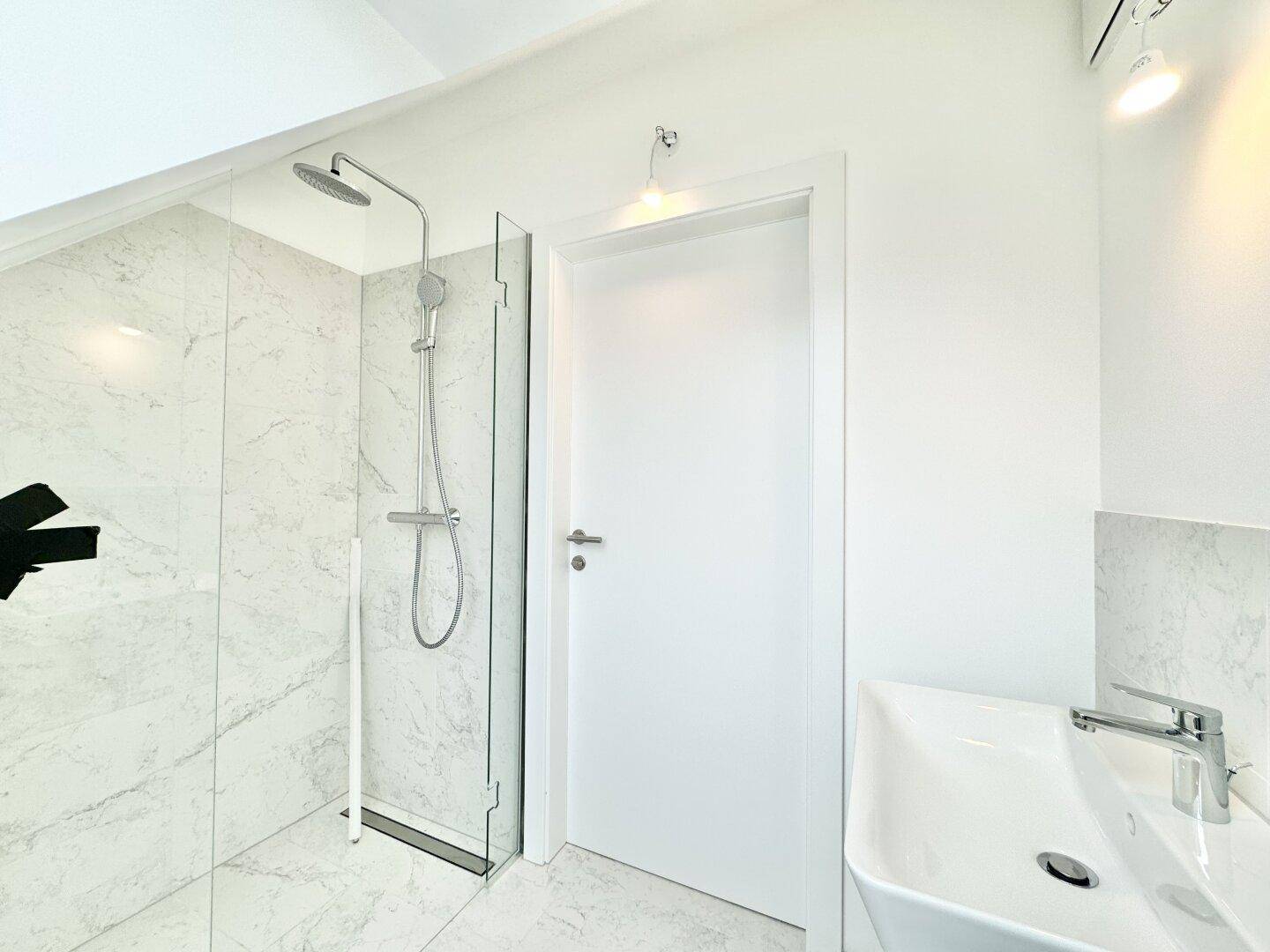 Modernes Badezimmer mit begehbarer Dusche, Regendusche und elegantem Waschbecken.