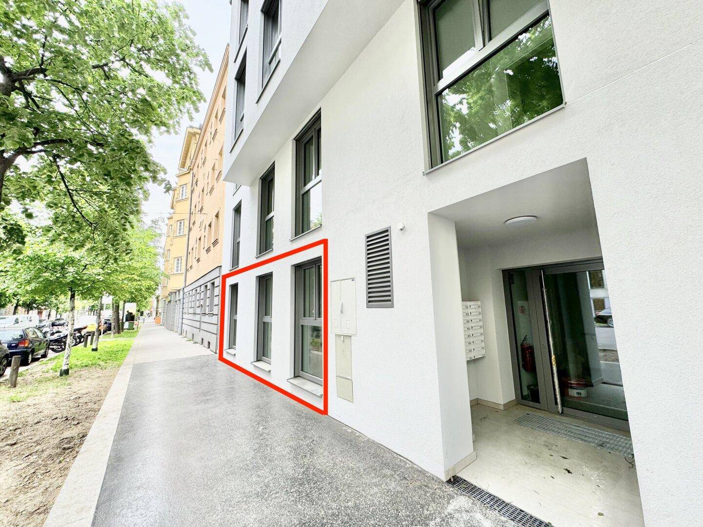 Außenansicht eines modernen Gebäudes an der Straße mit Eingangsbereich und Gehwegen.