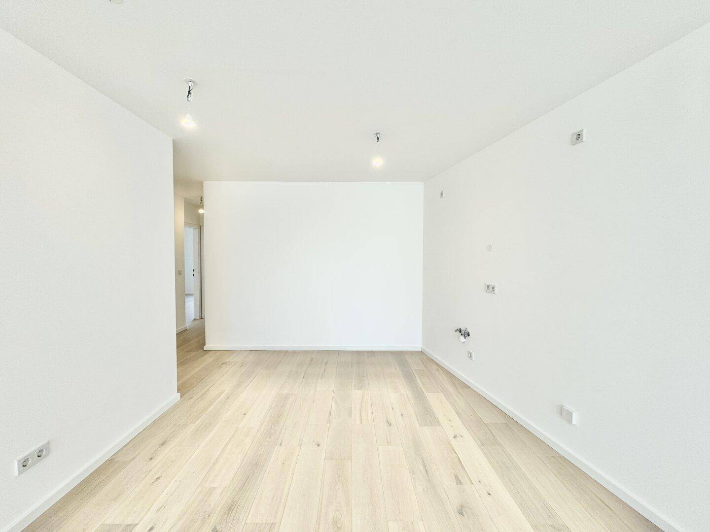 Geräumiger, heller Raum mit Holzboden und weißen Wänden, bietet flexible Gestaltungsmöglichkeiten.
