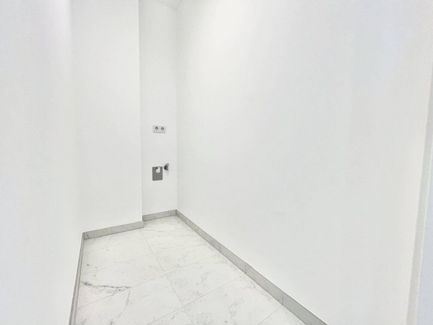 Kleiner Hauswirtschaftsraum mit Fliesenboden und Anschlüssen für Waschmaschine oder Trockner.