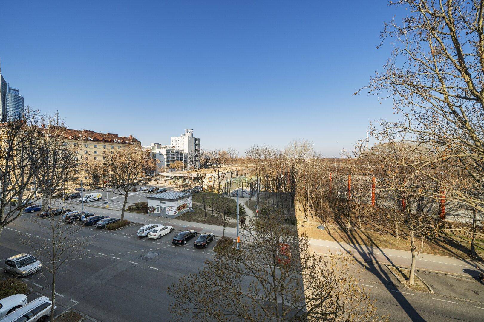 Weitläufiger Blick über die Stadt mit Bäumen und Gebäuden unter blauem Himmel.