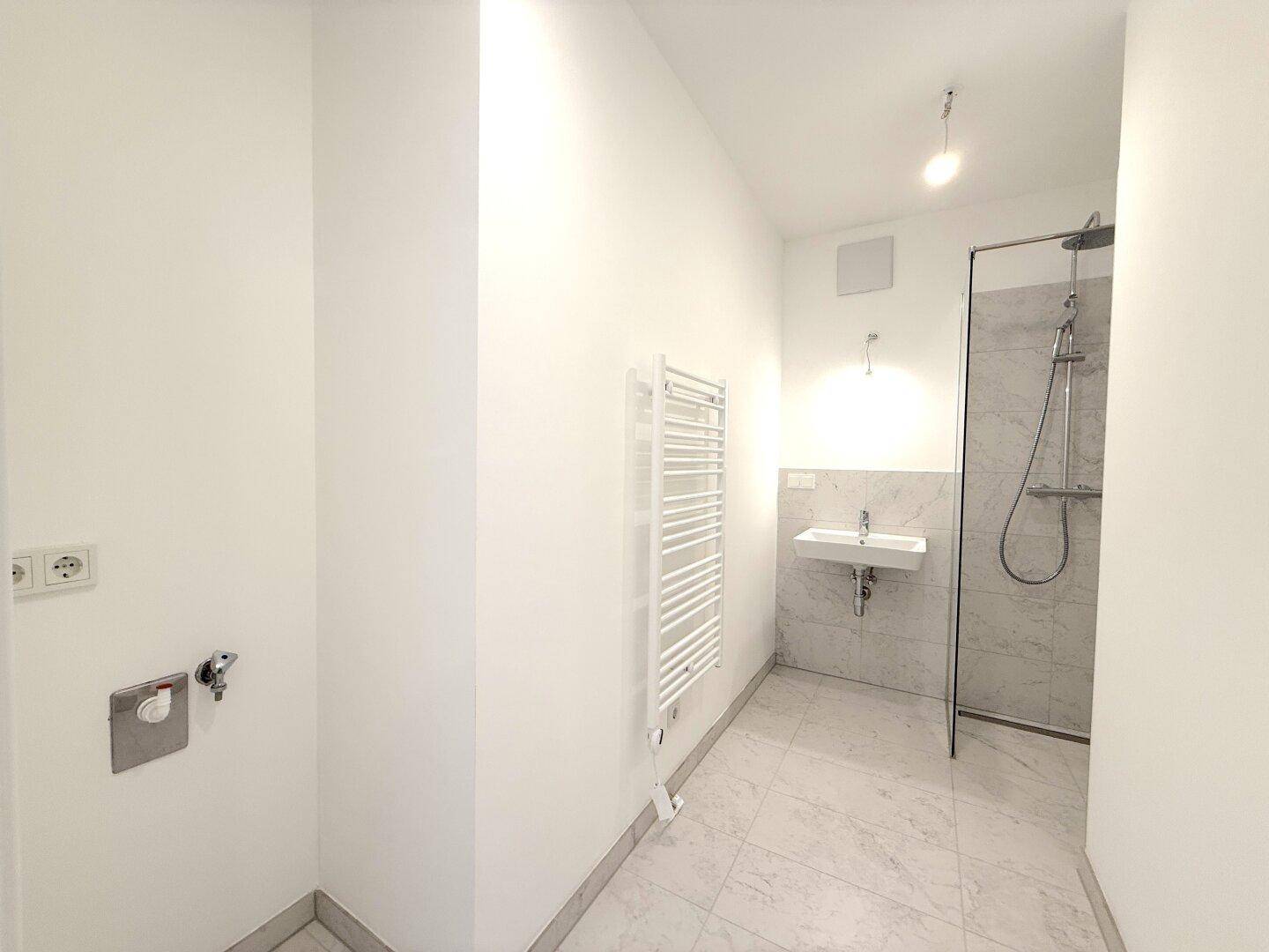 Modernes Badezimmer mit ebenerdiger Dusche, Marmorfliesen und einem beheizten Handtuchhalter.