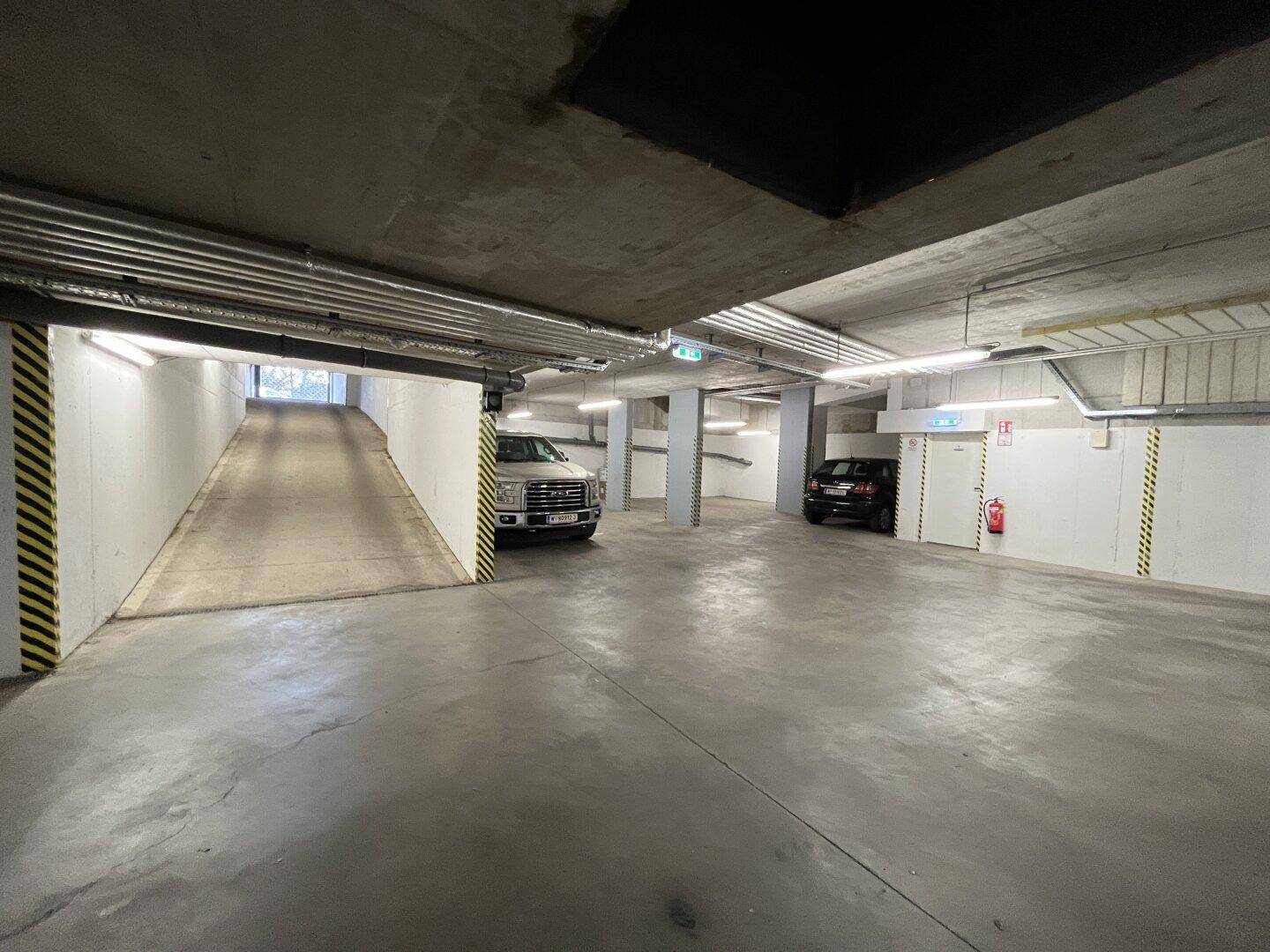 Geräumige Tiefgarage mit Zufahrtsrampe und mehreren Stellplätzen für Fahrzeuge.