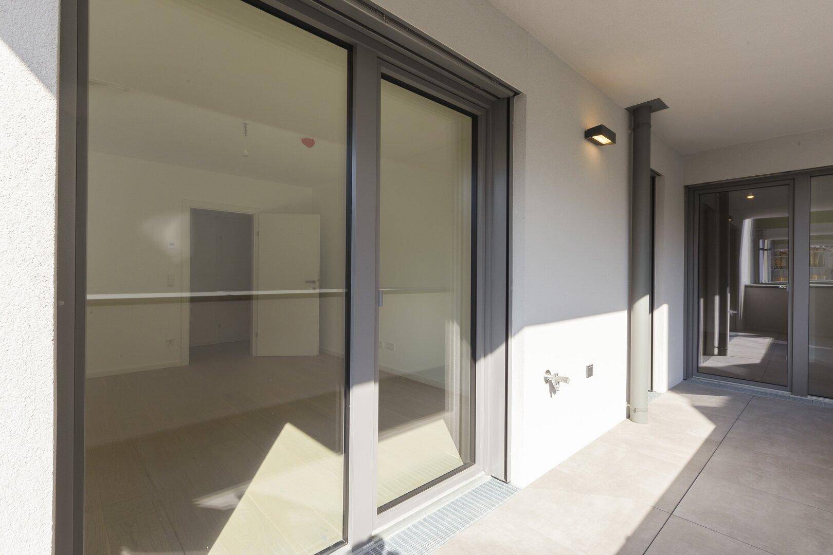 Geräumiger Balkon mit Schiebetür und Fliesenboden, ideal für Entspannung.
