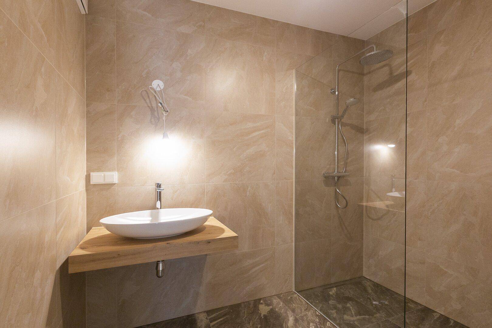 Modernes Badezimmer mit begehbarer Dusche und elegantem Waschbecken.