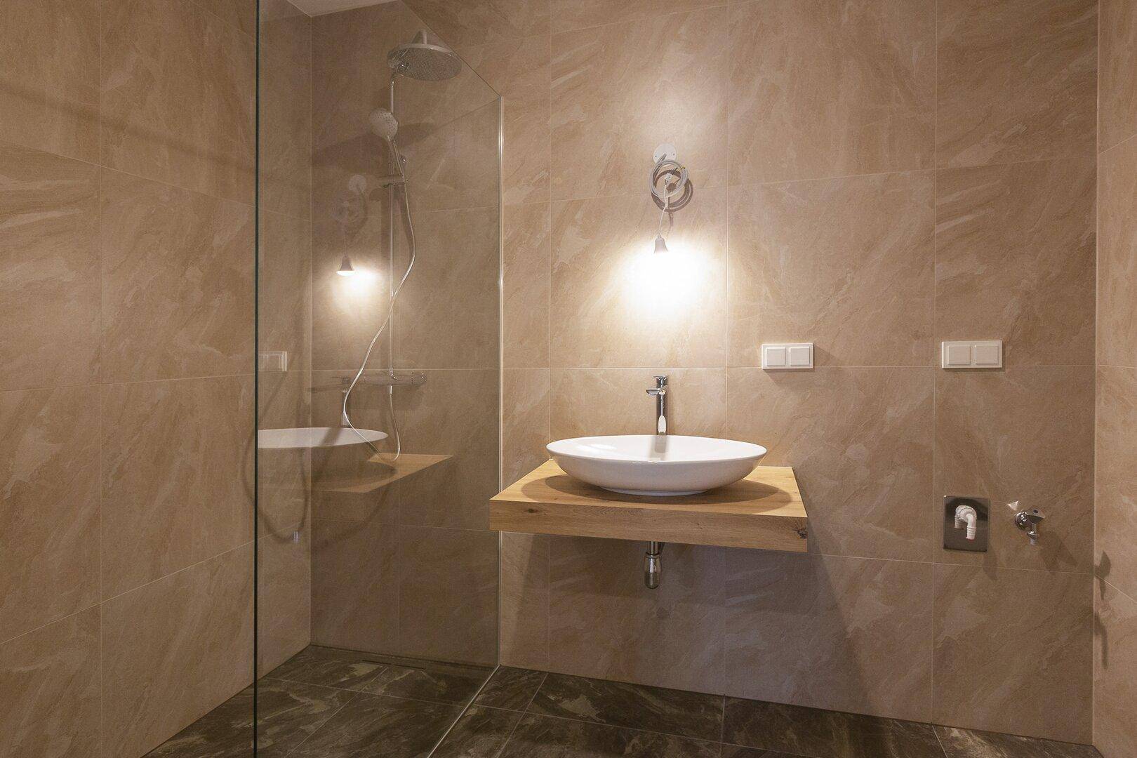 Elegantes Badezimmer mit beigefarbenen Fliesen, modernem Waschbecken und begehbarer Dusche.