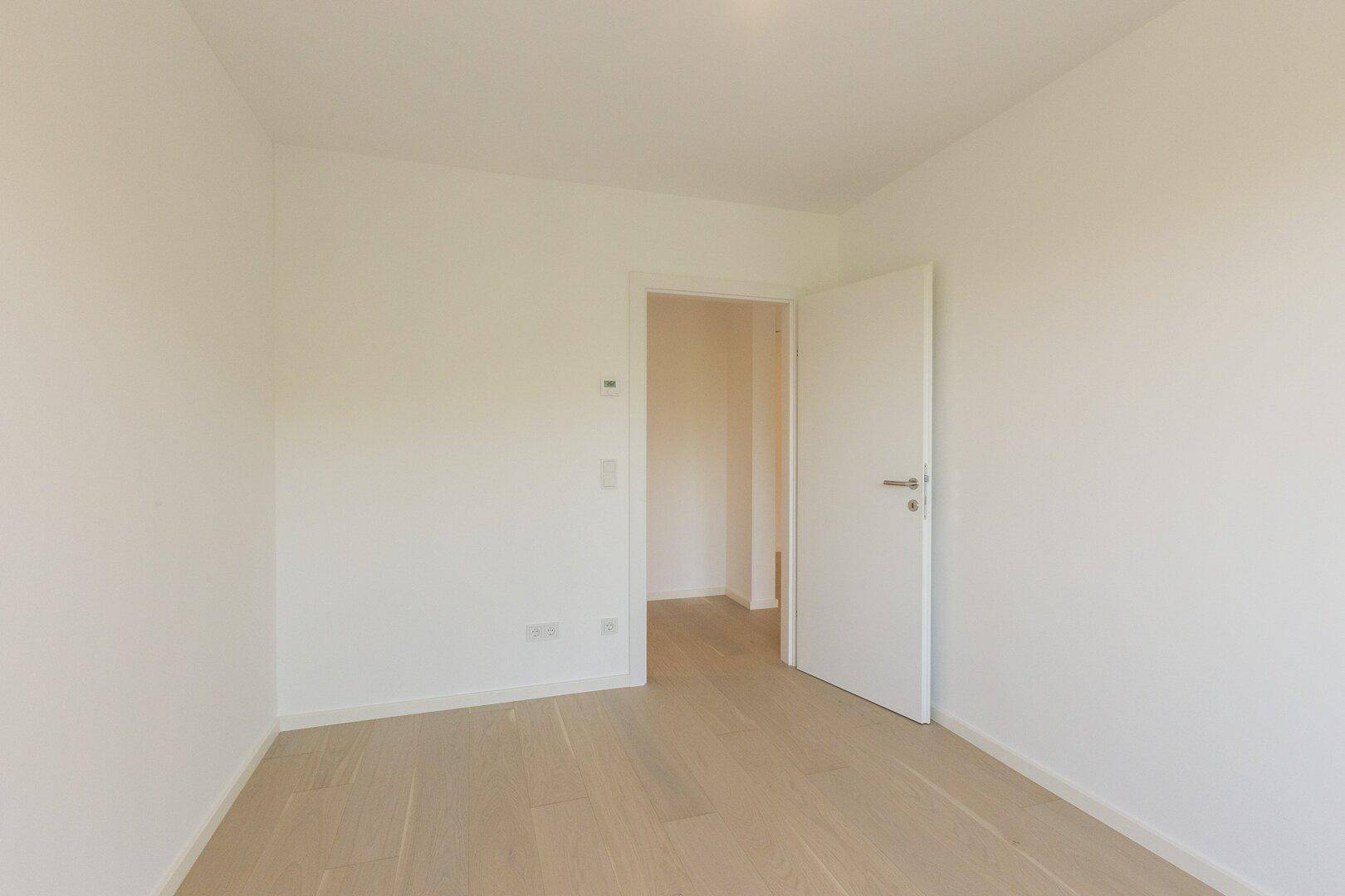 Helles Zimmer mit Holzboden und weiß gestrichenen Wänden, bereit zur Einrichtung.