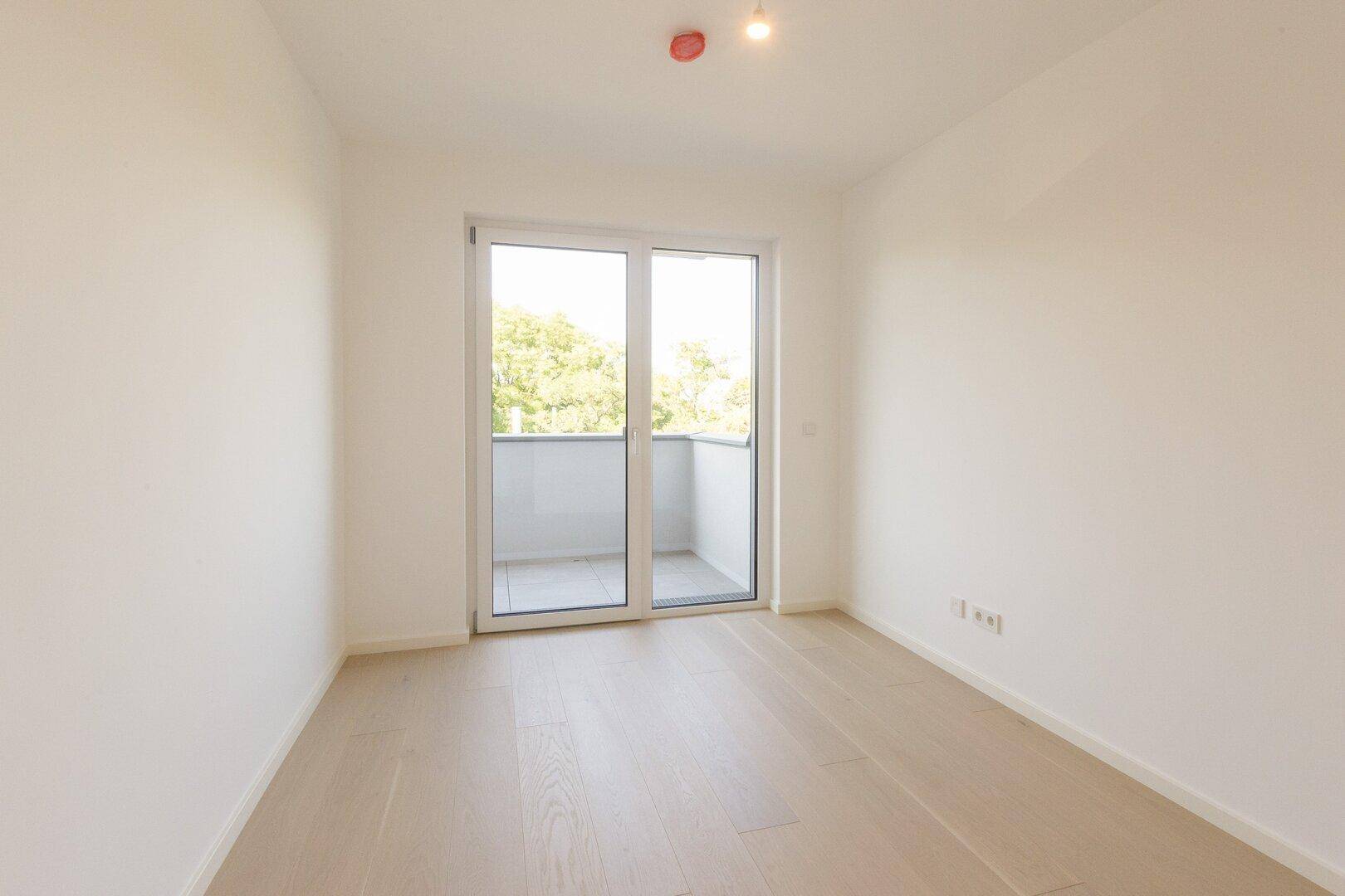 Helles Schlafzimmer mit Holzboden und direktem Zugang zum Balkon.