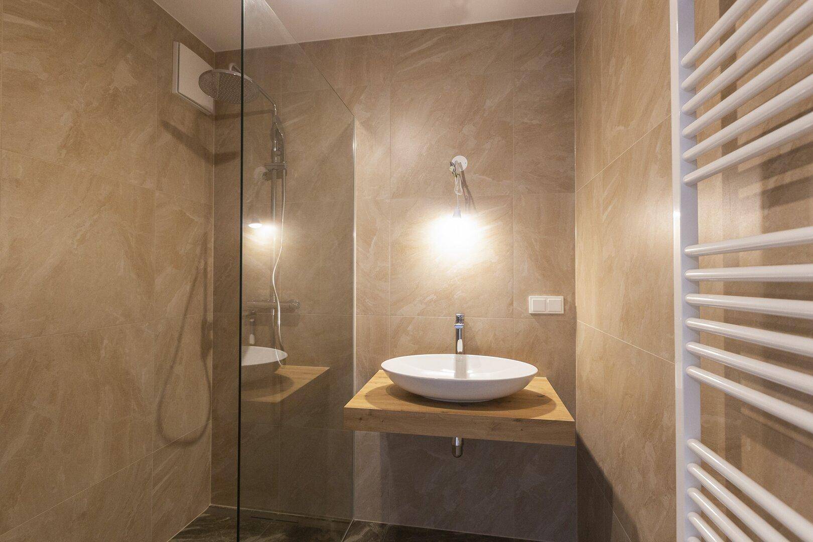 Elegantes Badezimmer mit begehbarer Dusche, modernem Waschbecken und beheiztem Handtuchhalter.