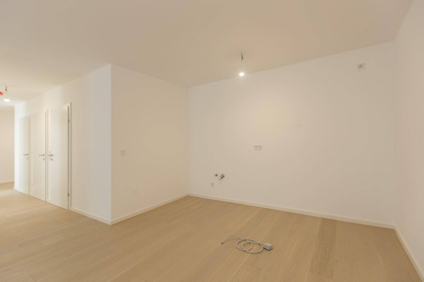 Heller Raum mit Holzboden und mehreren weißen Türen, möglicherweise ein Flur oder offener Bereich.