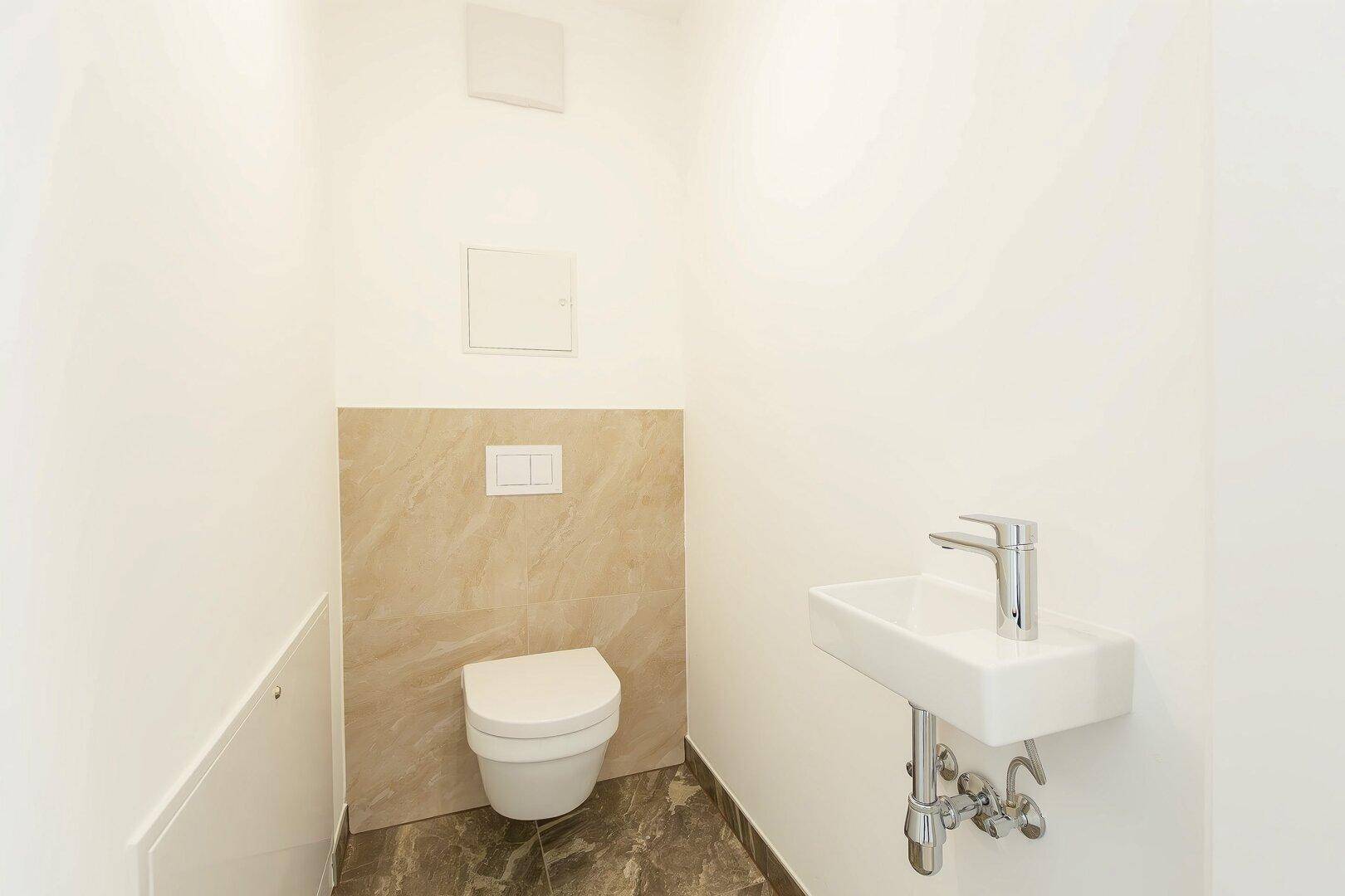 Modernes Gäste-WC mit wandhängender Toilette und kleinem Waschbecken.