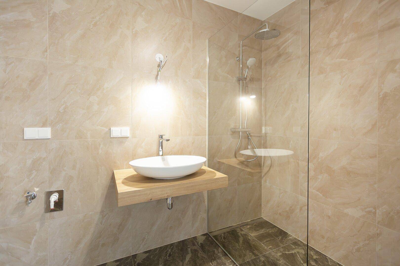Modernes Badezimmer mit begehbarer Dusche, Regenbrause und eleganten beigefarbenen Fliesen.