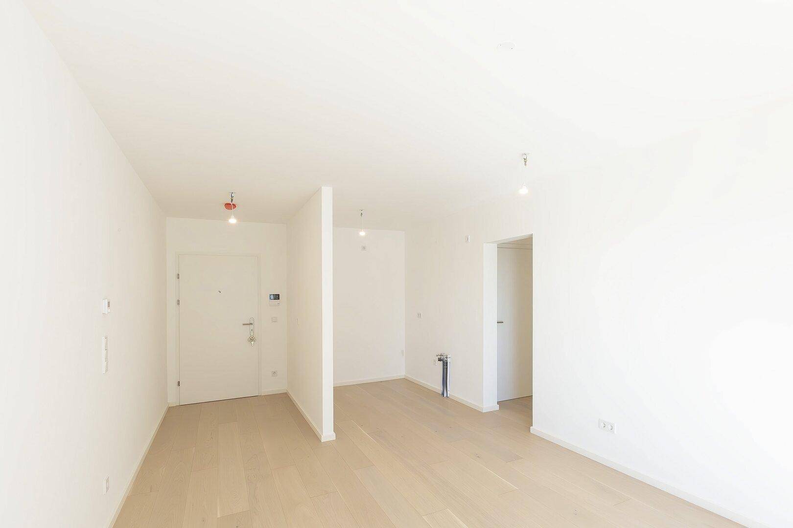 Heller Eingangsbereich mit Holzboden und weißer Eingangstür, einladend gestaltet.