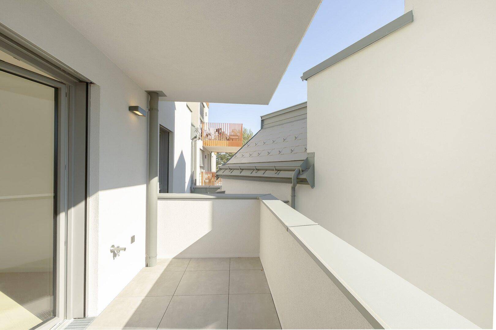Sonniger Balkon mit modernem Geländer und Blick auf die umliegenden Gebäude.