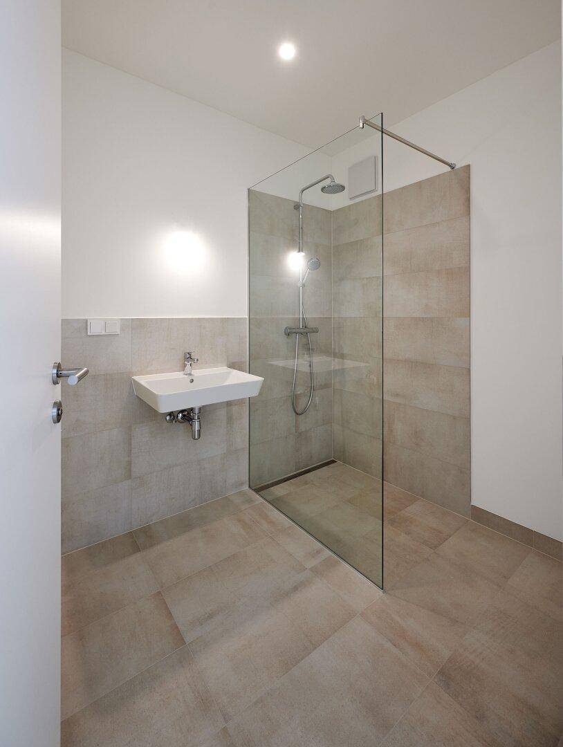 Modernes Badezimmer mit begehbarer Dusche, Wandfliesen und einem einzelnen Waschbecken.