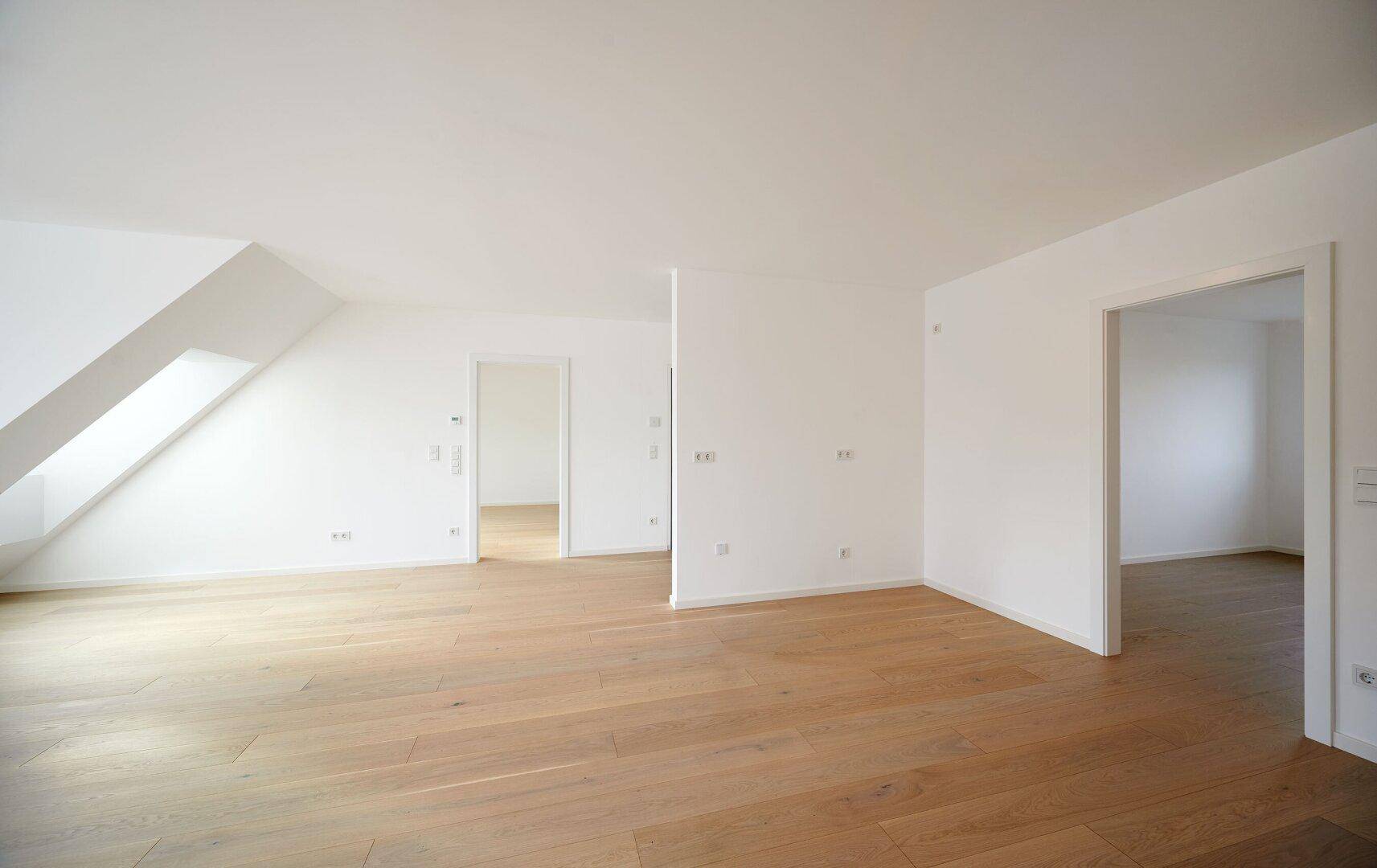 Geräumiges, helles Zimmer mit Holzboden und Zugang zu weiteren Räumen, ideal für individuelle Gestaltung.