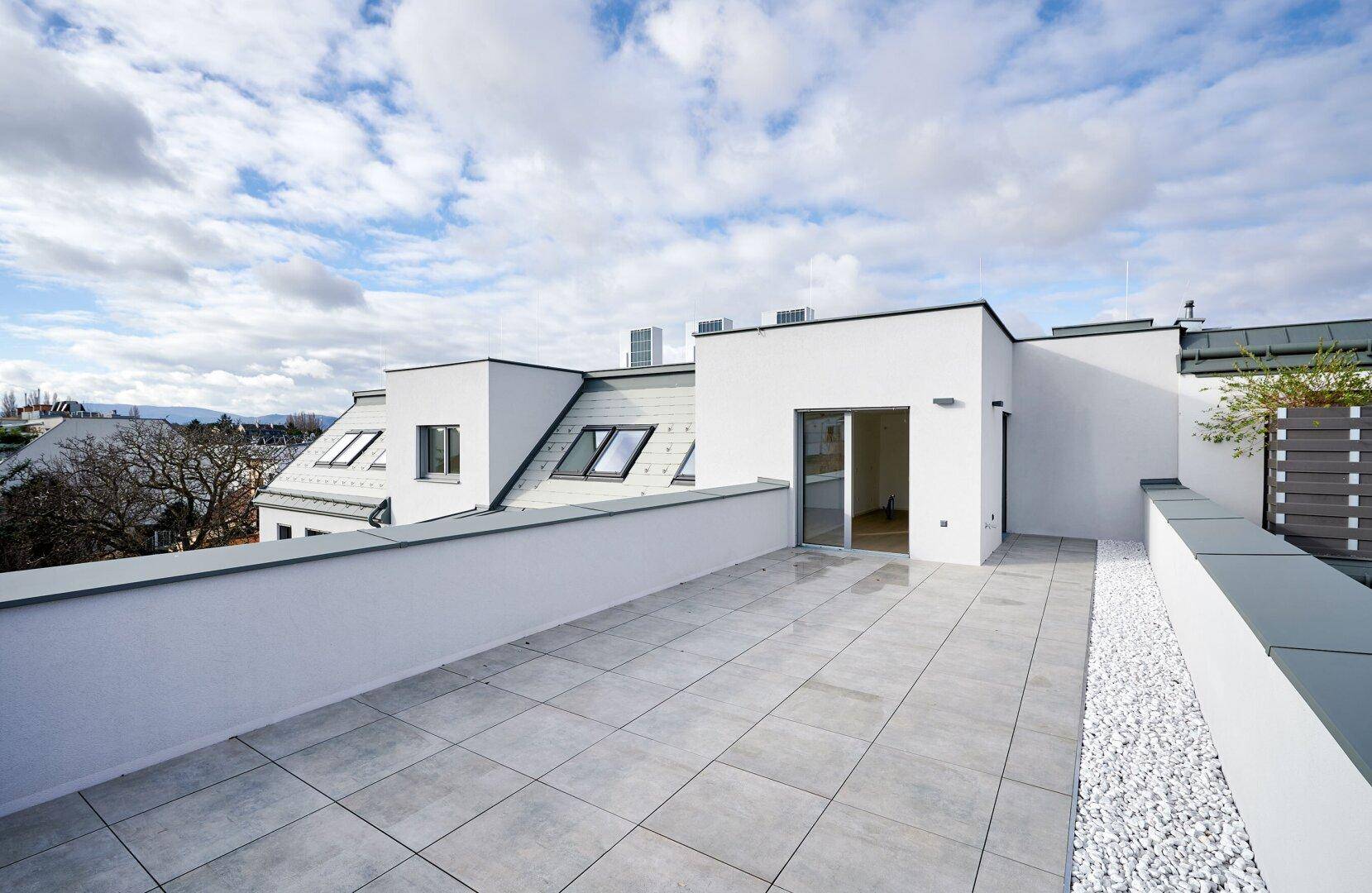 Weitläufige Dachterrasse mit modernen Fliesen und Blick auf die umliegenden Gebäude und Dächer.