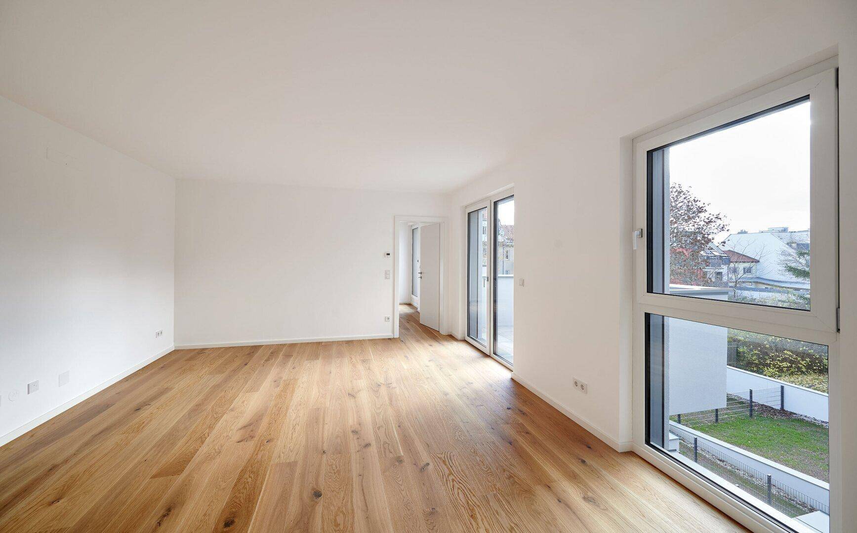 Großes, helles Wohnzimmer mit Holzboden und weitem Blick nach draußen, ideal für die Gestaltung.