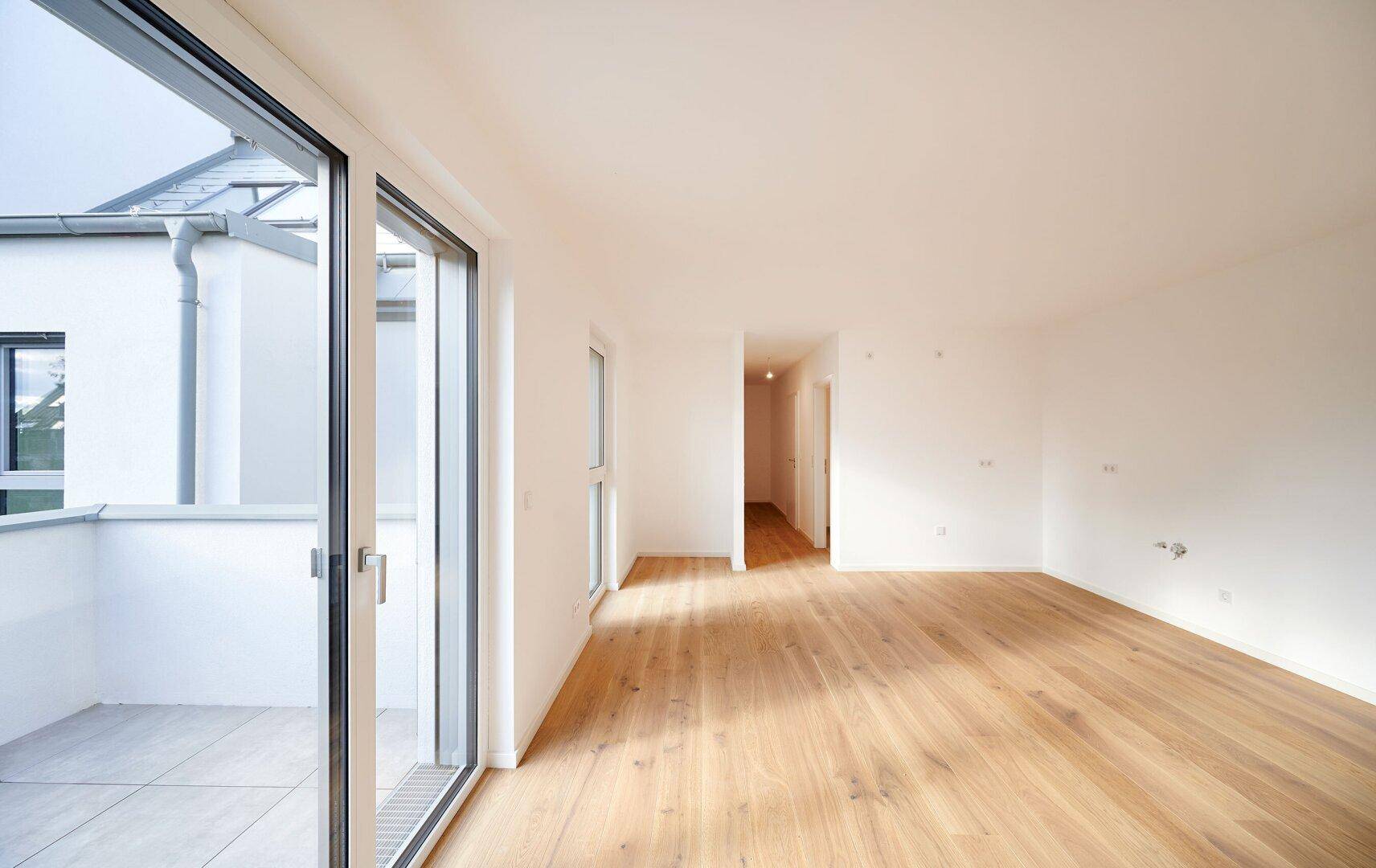 Lichtdurchflutetes Wohnzimmer mit Holzboden und Schiebetür zum Außenbereich, bereit für die Einrichtung.