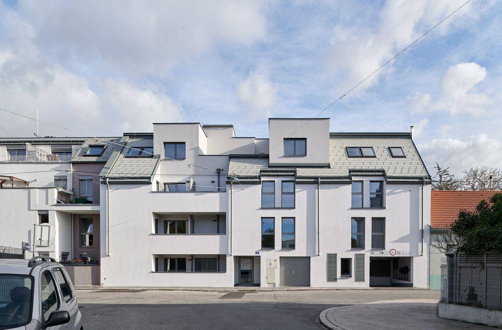 Ansicht der modernen Wohngebäude von der Straße mit klarem Himmel und leichter Bewölkung.